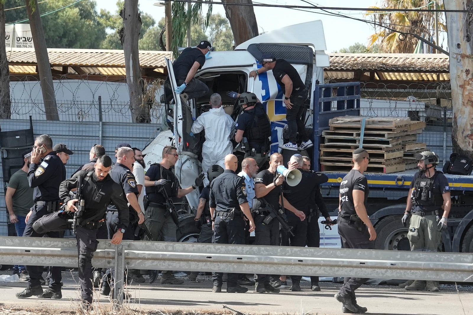 Israeli police climb on a truck that rammed into a bus stop near the headquarters of Israel's Mossad spy agency, wounding dozens of people, according to Israel's Magen David Adom rescue service in Tel Aviv, Israel, Sunday, Oct. 27, 2024. (AP Photo/Oded Balilty)