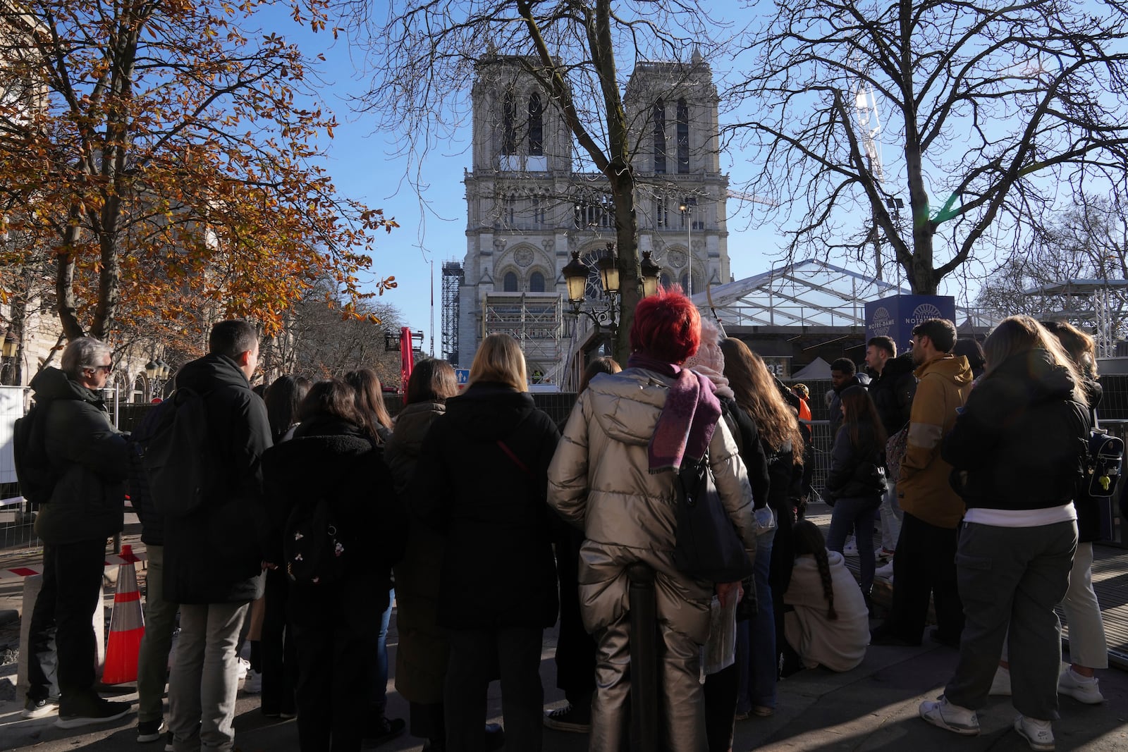 Tourists watch Notre-Dame cathedral from behind a security perimeter, Thursday, Nov. 28, 2024 in Paris. (AP Photo/Michel Euler)