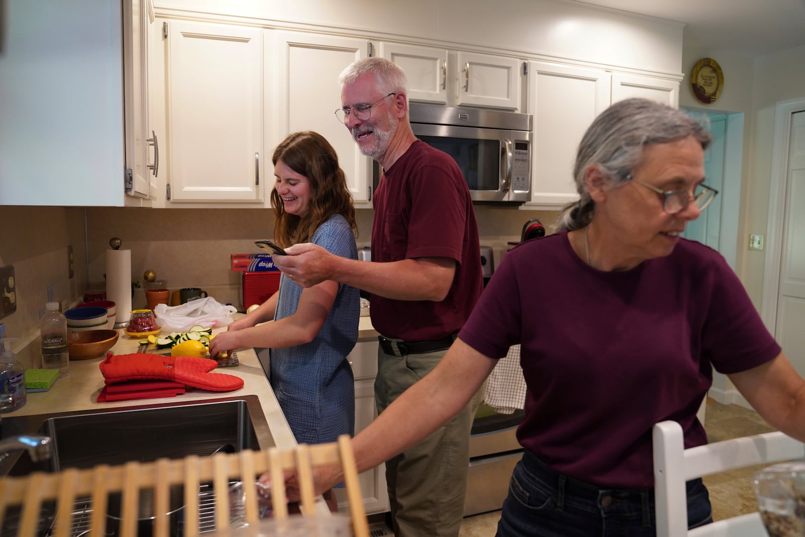 A month before entering the Franciscan Sisters, T.O.R. of Penance of the Sorrowful Mother as a postulant, Zoey Stapleton, left, cooked dinner with her parents Tom and Peggy in Palmyra, Pa., Tuesday, July 2, 2024. (AP Photo/Jessie Wardarski)