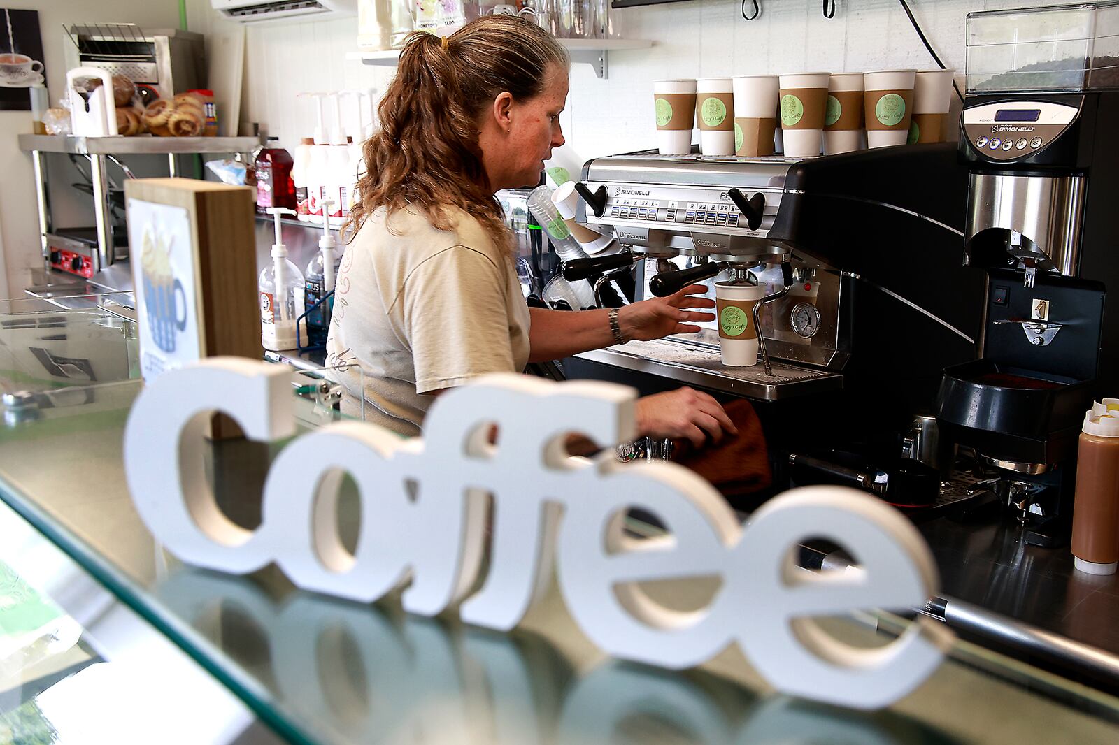 Kerry Schooler makes a cappuccino in Kerry's Cafe's new brick and mortar location at the intersection of South Yellow Springs Street and West Possum Road Monday, July 29, 2024. BILL LACKEY/STAFF