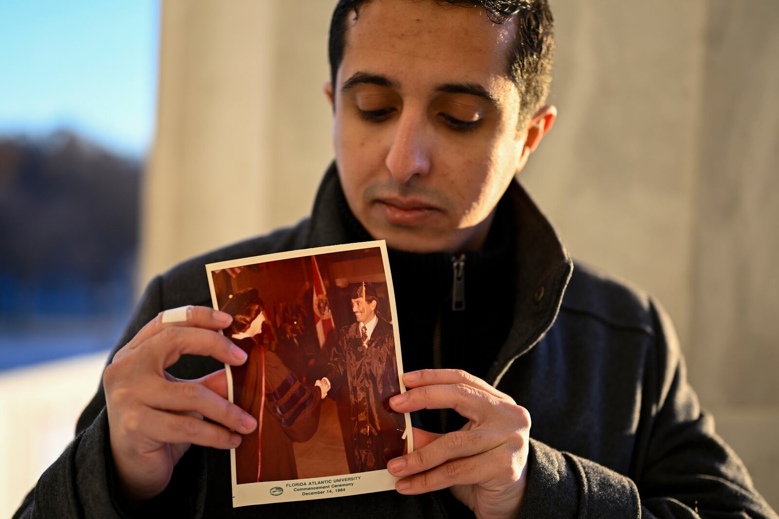 Ibrahim Almadi holds a photo of his father Saad Almadi graduating from college in 1984, in Washington Monday, Dec. 23, 2024. Saad Almadi, a dual U.S.-Saudi citizen was jailed for social media posts critical of the kingdom's crown prince. He was released from a Saudi prison in March 2023 and banned from returning to his home in south Florida. (AP Photo/John McDonnell)