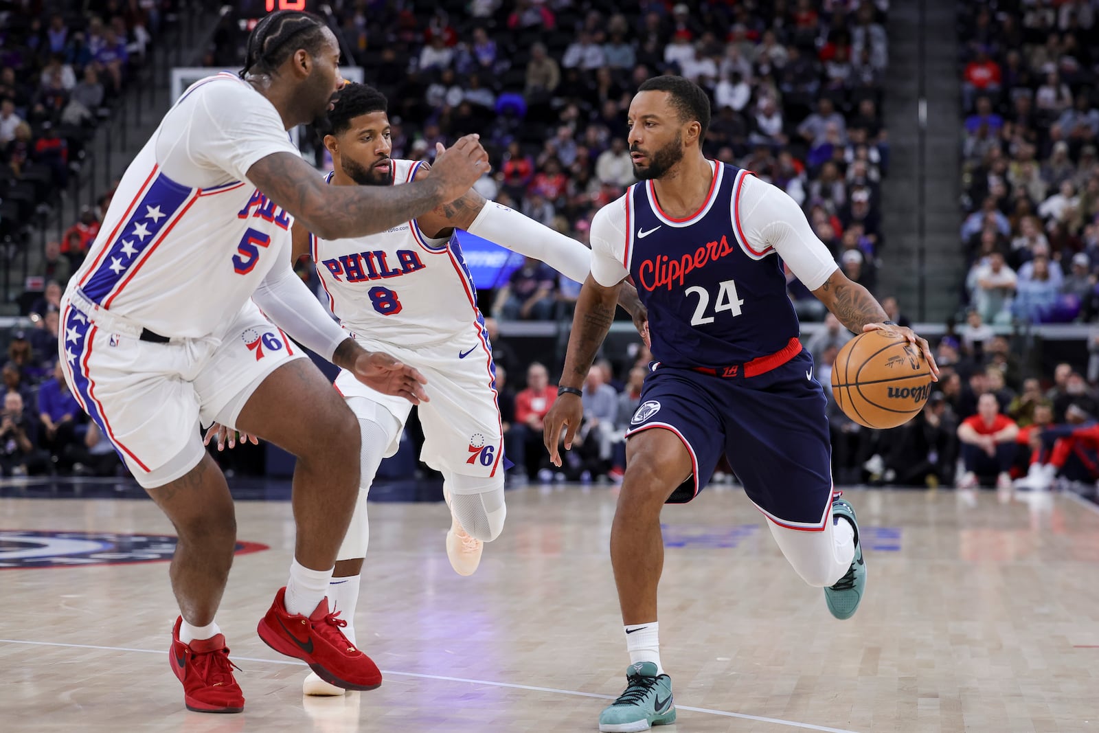 Los Angeles Clippers guard Norman Powell, right, drives against Philadelphia 76ers center Andre Drummond, left, and forward Paul George during the second half of an NBA basketball game, Wednesday, Nov. 6, 2024, in Inglewood, Calif. (AP Photo/Ryan Sun)