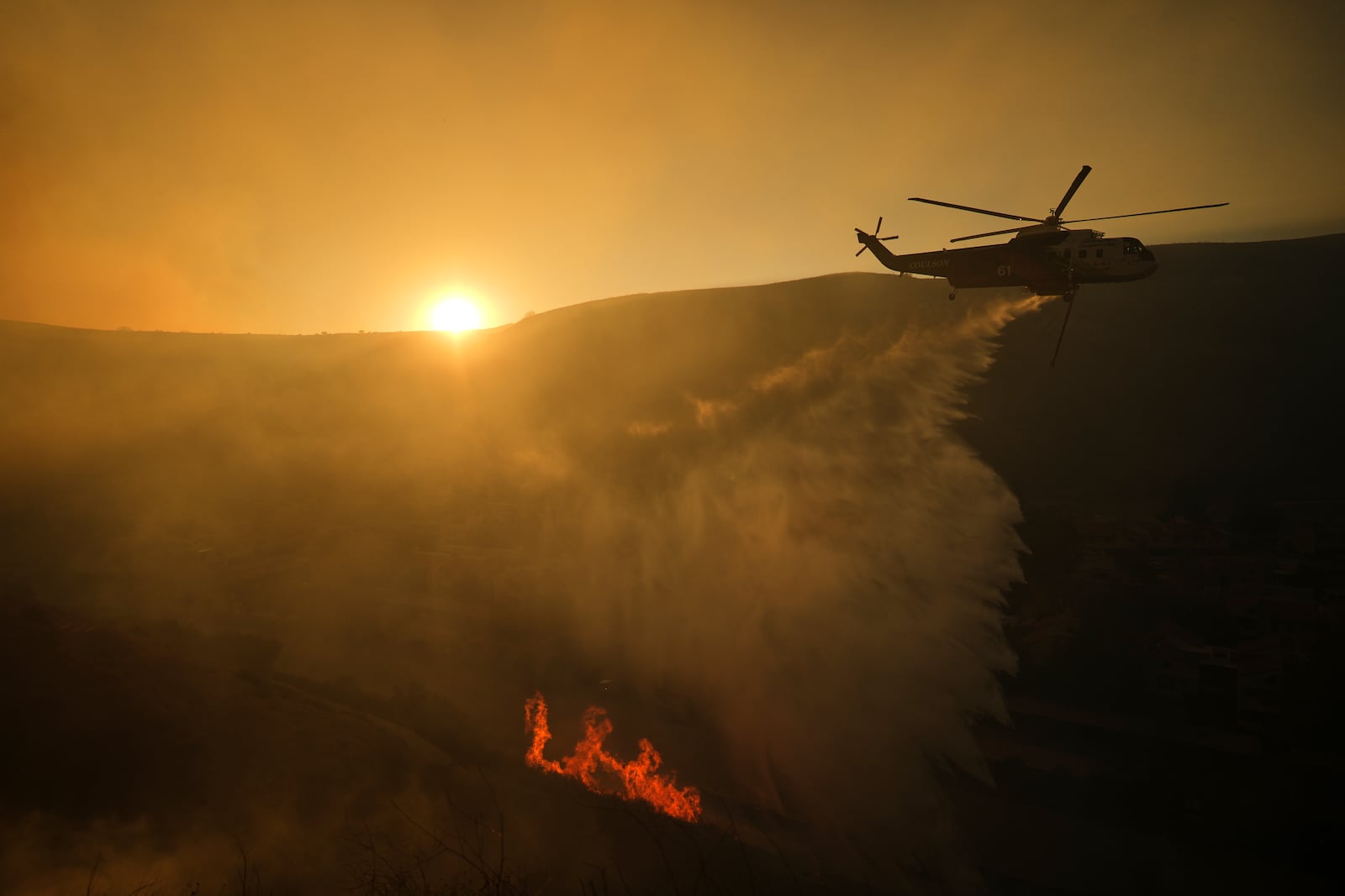 A helicopter flies over the Kenneth Fire, Thursday, Jan. 9, 2025, in the West Hills section of Los Angeles. (AP Photo/Eric Thayer)