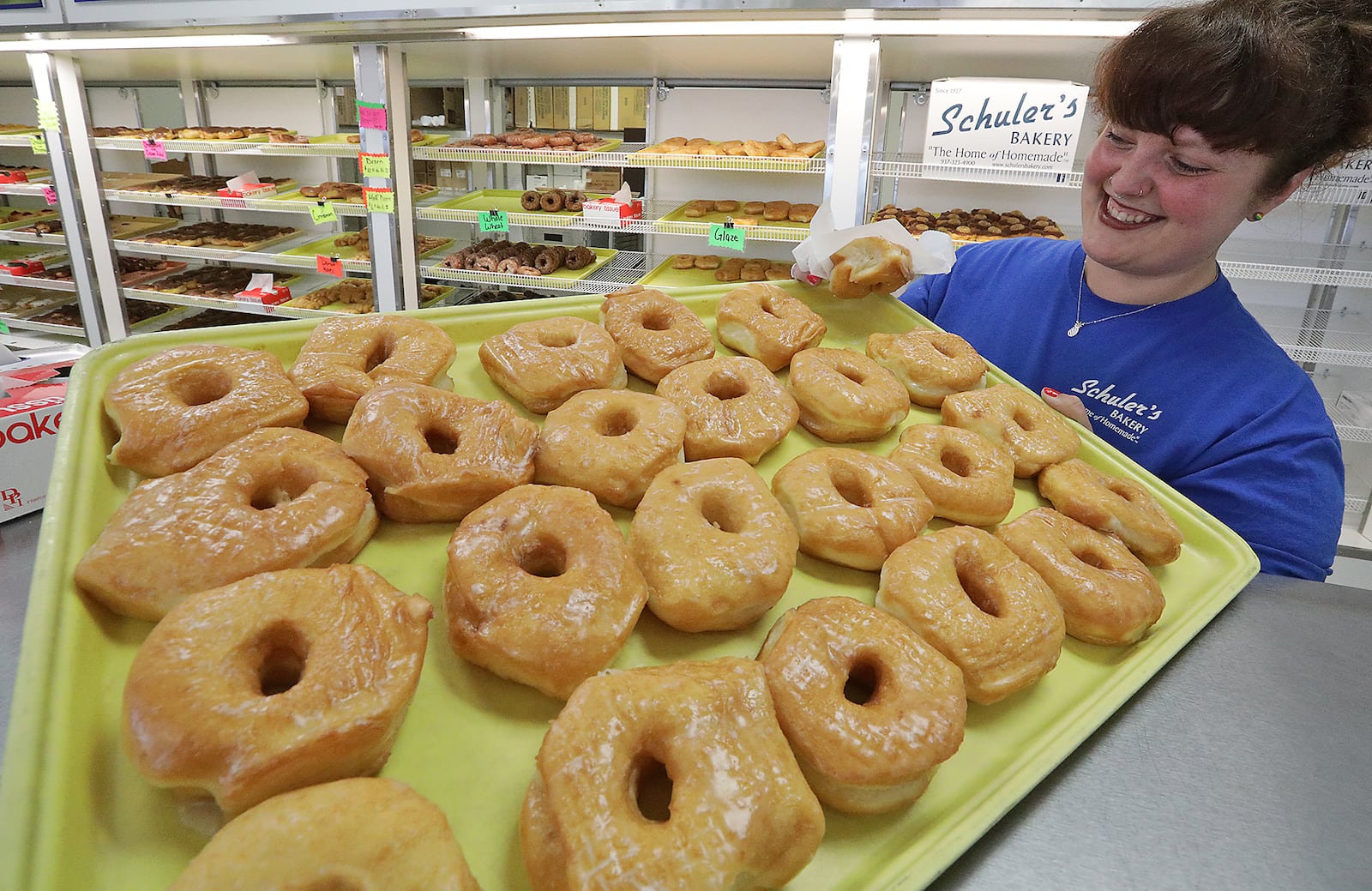 Lindsey Haerr picks some glazed donuts from a tray at Schuler's Bakery in Springfield on June 3, 2022. The bakery, which is famous for their donuts, was selling even more of the sticky fried dough for National Donut Day. BILL LACKEY/STAFF