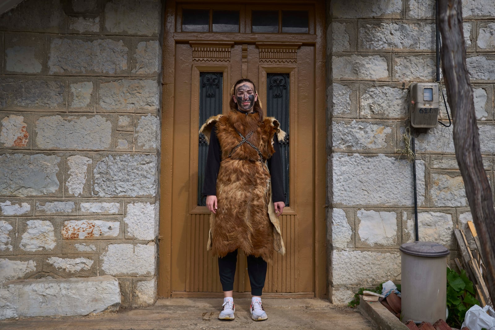 Asimina Philipou, 16 ,poses for a portrait, dressed in animal skins and heavy bronze bells, as part of carnival celebrations in Distomo, a village in central Greece, on Monday, March 3, 2025. (AP Photo/Petros Giannakouris)