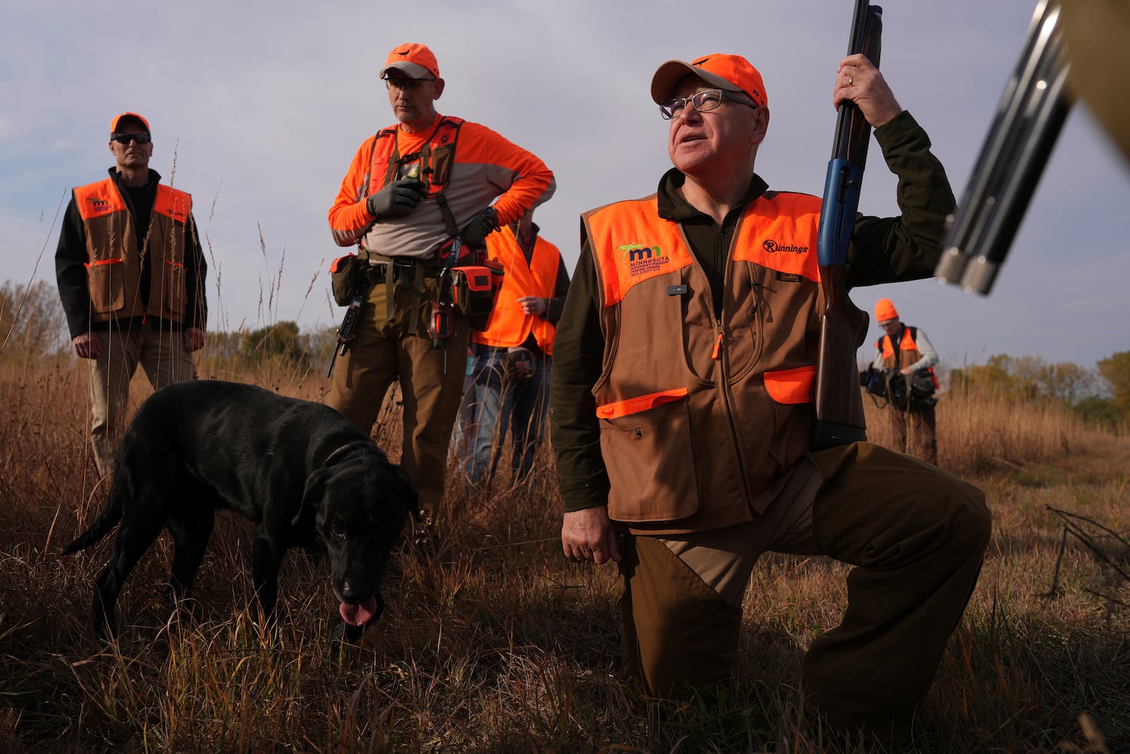 Flanked by his Secret Service detail, Minnesota Governor and Democratic Vice Presidential candidate Tim Walz stops during a break to give water to the hunting dogs during the annual Minnesota Governor's Pheasant Hunting Opener, Saturday, Oct. 12, 2024, near Sleepy Eye, Minn. (Anthony Souffle/Star Tribune via AP)