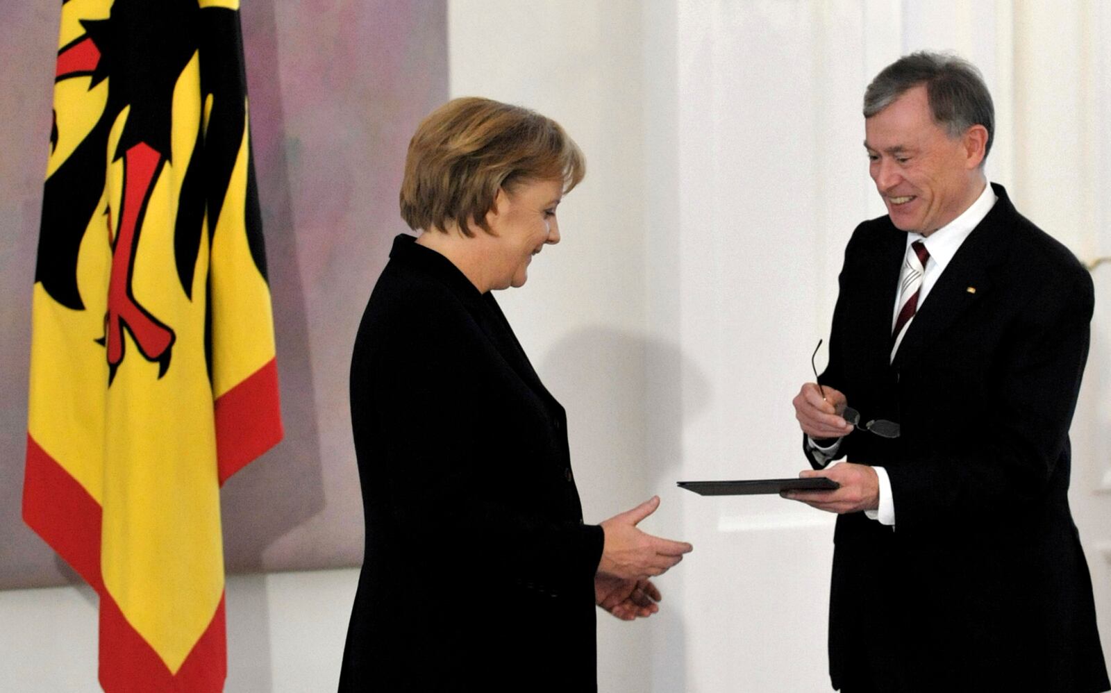 FILE - German President Horst Koehler, right, hands over the credentials to re-elected German chancellor Angela Merkel during a ceremony at the president's residence Bellevue Castle in Berlin, Germany, Wednesday, Oct. 28, 2009. (AP Photo/Kai-Uwe Knoth, File)