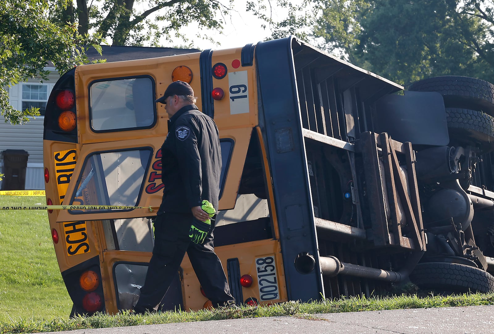 Clark County Sheriff's Lt. Kris Schultz walks past a Northwestern School District bus that was involved in a crash in Lawrenceville, Ohio, Tuesday, Aug. 22, 2023. (BILL LACKEY/STAFF)