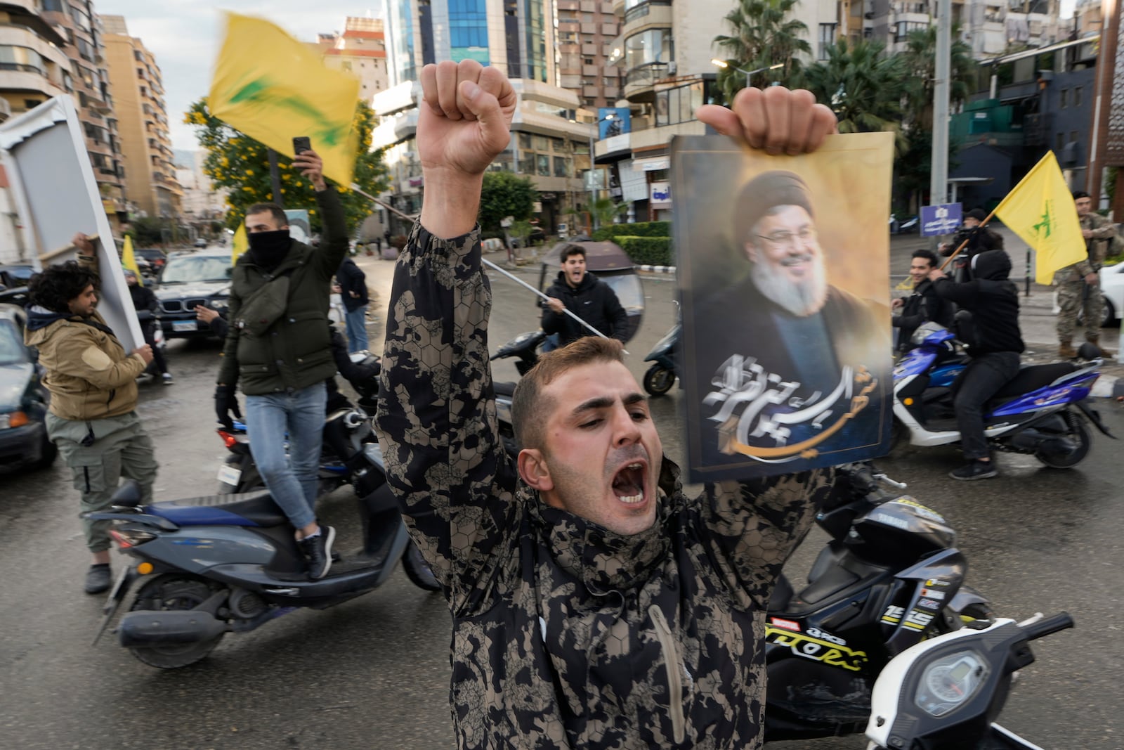 A man celebrates carrying a picture of slain Hezbollah leader Hassan Nasrallah in Dahiyeh, Beirut, Lebanon, following a ceasefire between Israel and Hezbollah that went into effect on Wednesday, Nov. 27, 2024. (AP Photo/Bilal Hussein)