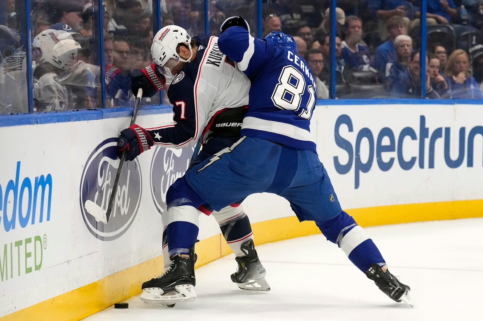 Tampa Bay Lightning defenseman Erik Cernak (81) pins Columbus Blue Jackets center Sean Kuraly (7) to the dasher as he tries to play the puck during the first period of an NHL hockey game Tuesday, Dec. 17, 2024, in Tampa, Fla. (AP Photo/Chris O'Meara)