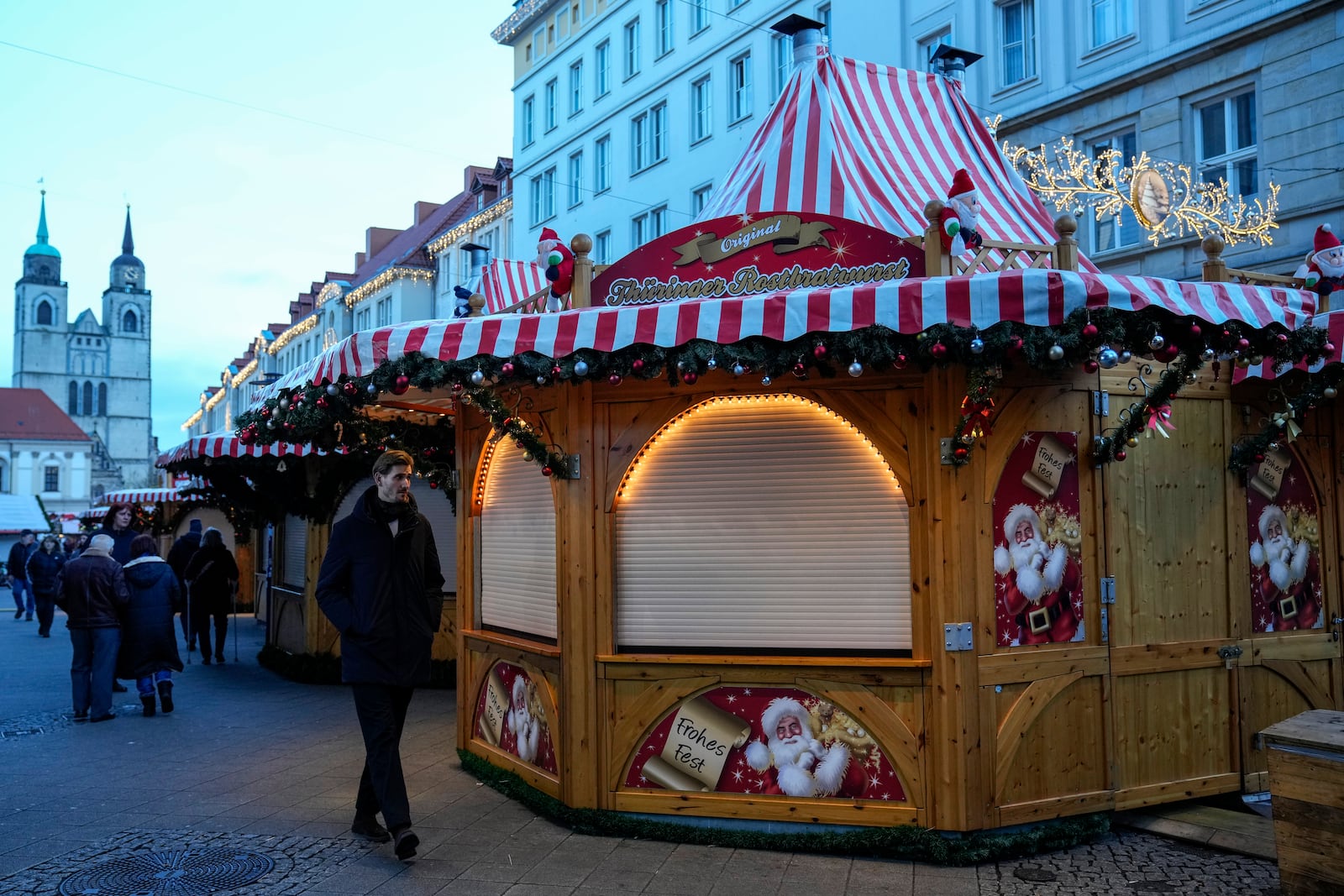 People walk at the Christmas Market, where a car drove into a crowd on Friday evening, in Magdeburg, Germany, Sunday, Dec. 22, 2024. (AP Photo/Ebrahim Noroozi)