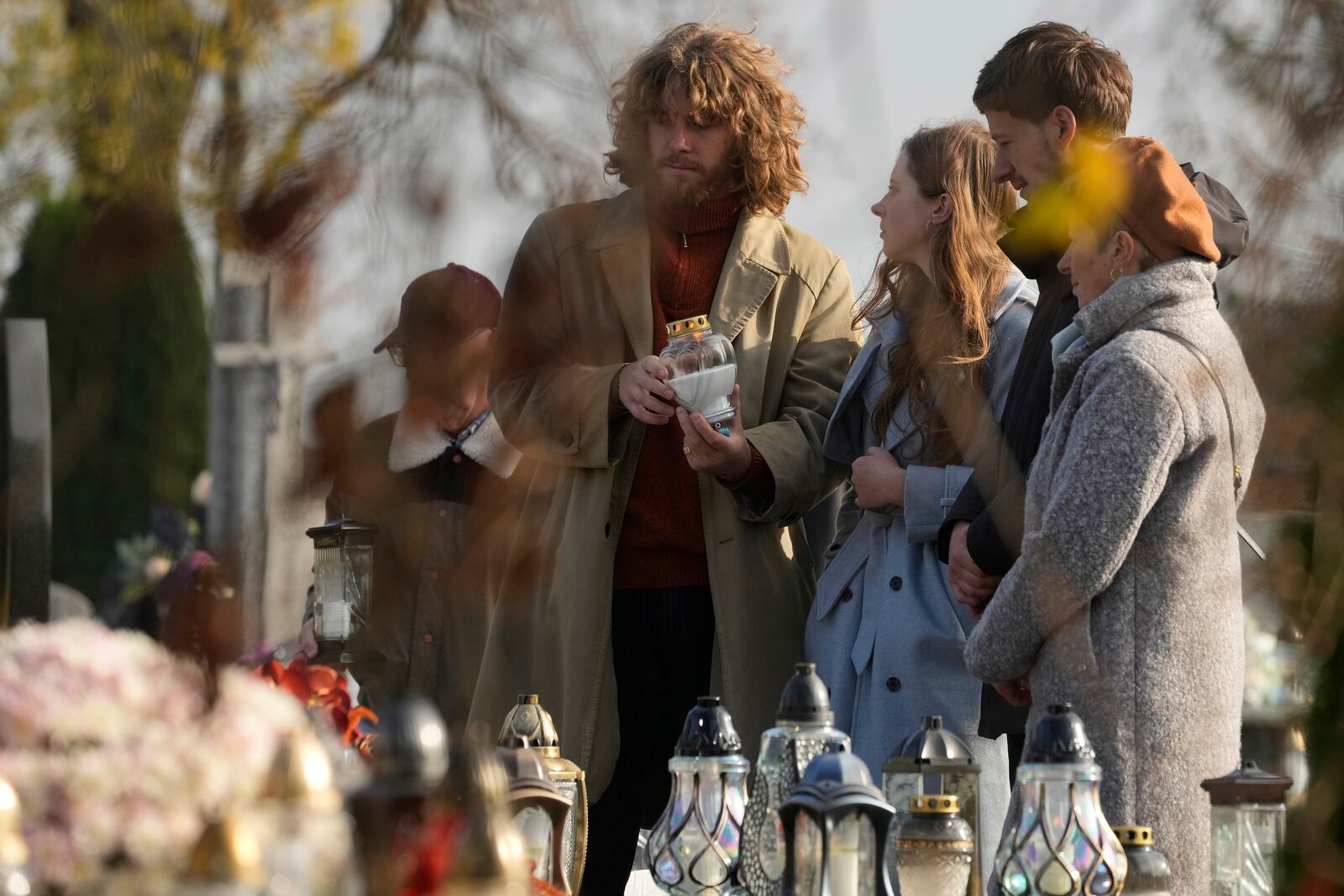 A man lights a candle at a grave on All Saints' Day, a time for reflecting on those who have died, in Zakroczym near Warsaw, Polan, on Friday Nov. 1, 2024. (AP Photo/Czarek Sokolowski)