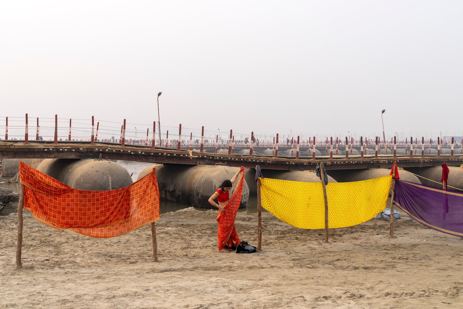 A Hindu woman devotee adjusts her saree as she changes after taking bath at the confluence of the Ganges, the Yamuna and the mythical Saraswati rivers, a day before the official beginning of the 45-day-long Maha Kumbh festival, in Prayagraj, India, Sunday, Jan. 12, 2025. (AP Photo/Ashwini Bhatia)