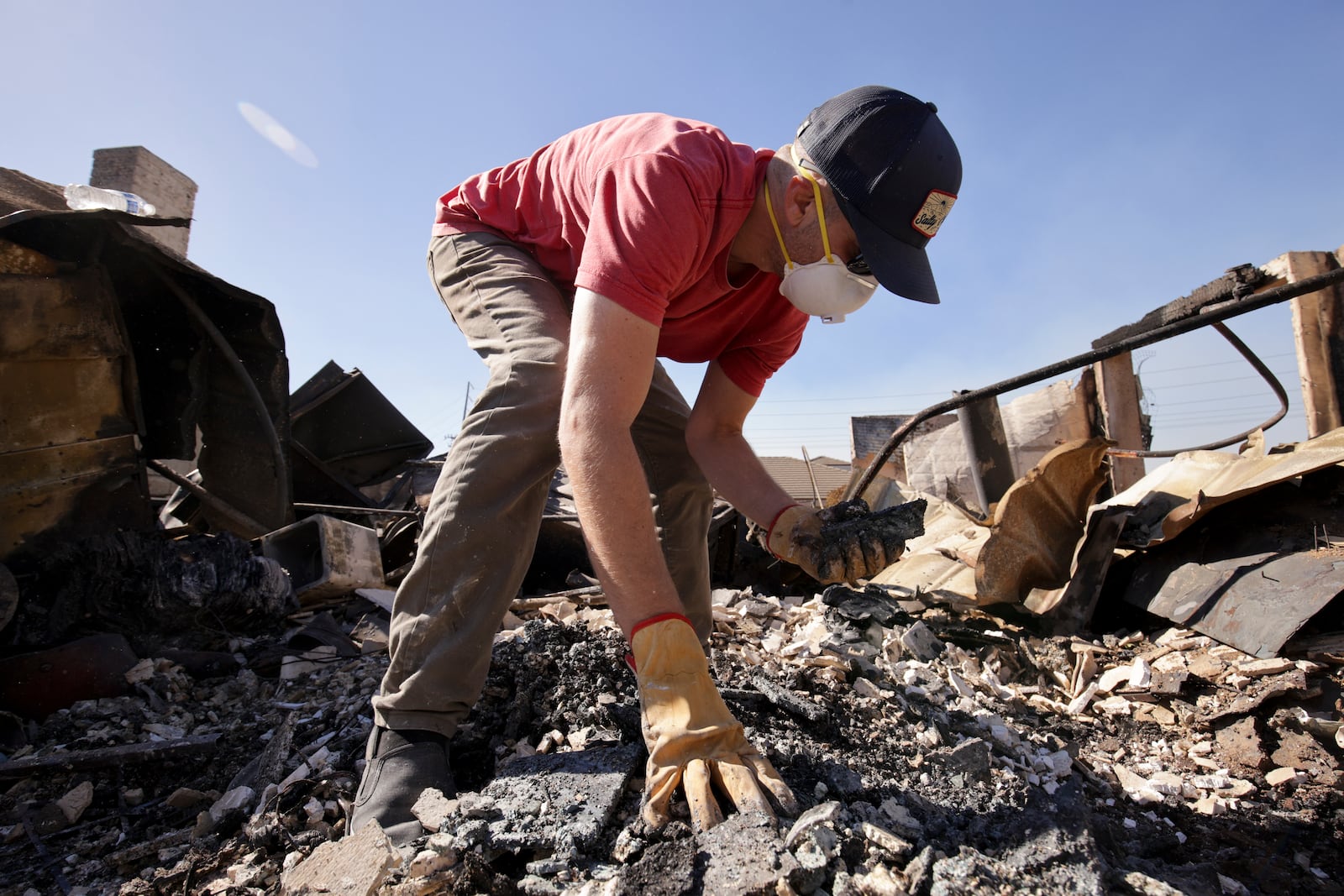 Todd Howard sifts through the remains of his parents' fire-ravaged property after the Mountain Fire swept through, Thursday, Nov. 7, 2024, in Camarillo, Calif. (AP Photo/Ethan Swope)