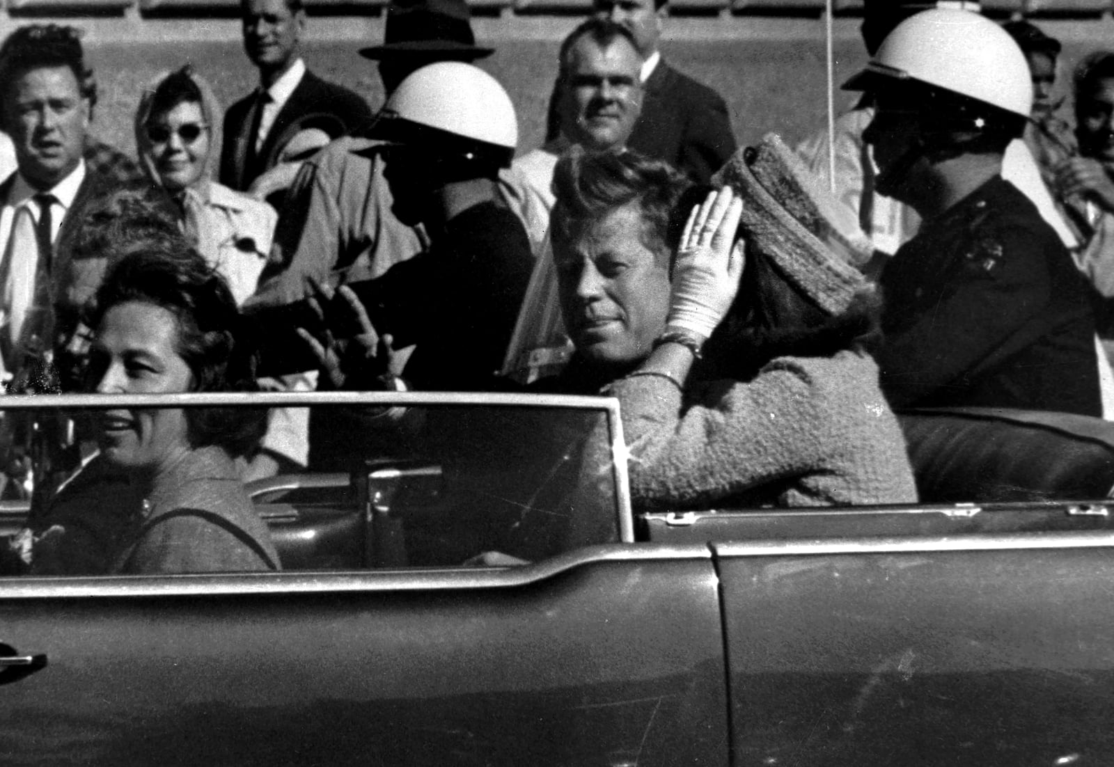 FILE - President John F. Kennedy waves from his car in a motorcade approximately one minute before he was shot, Nov. 22, 1963, in Dallas. Riding with President Kennedy are first lady Jacqueline Kennedy, right, Nellie Connally, second from left, and her husband, Texas Gov. John Connally, far left. (AP Photo/Jim Altgens, File)