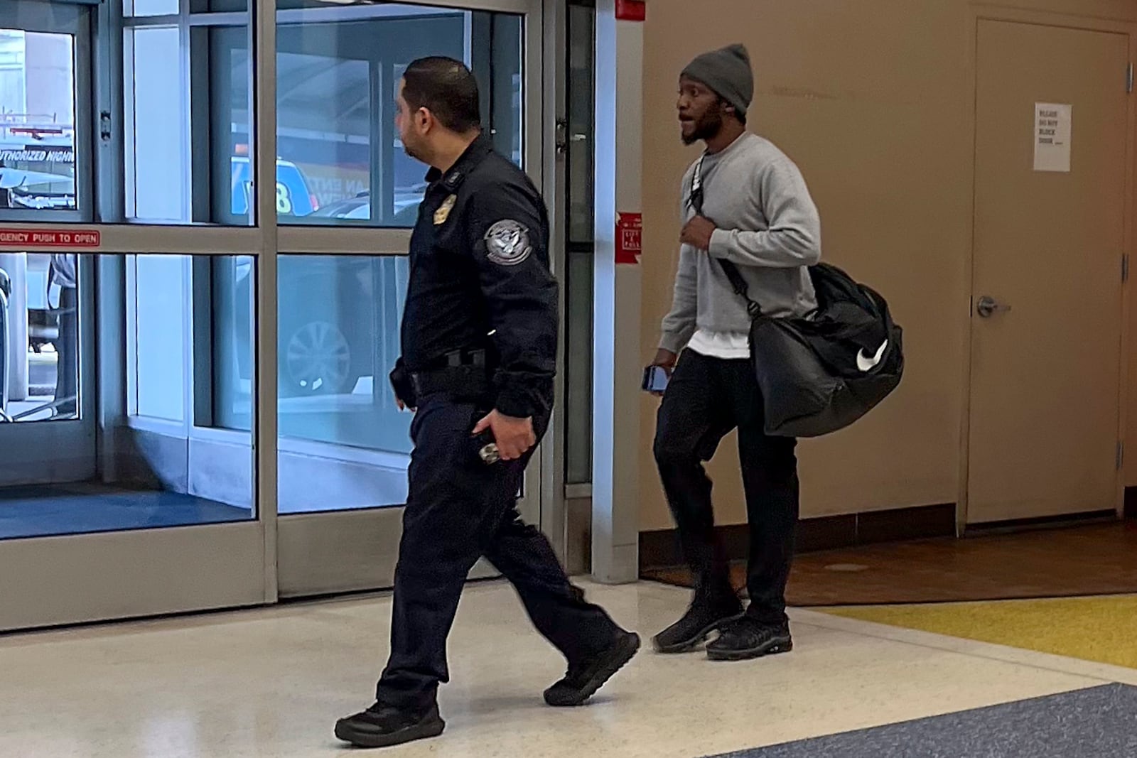 One of the six American prisoners flown from Kuwait to New York on Wednesday, March 12, 2025, right, is escorted by a Customs and Border Protection agent out of Terminal 7 at John F. Kennedy International Airport in New York. (AP Photo/Pamela Smith)