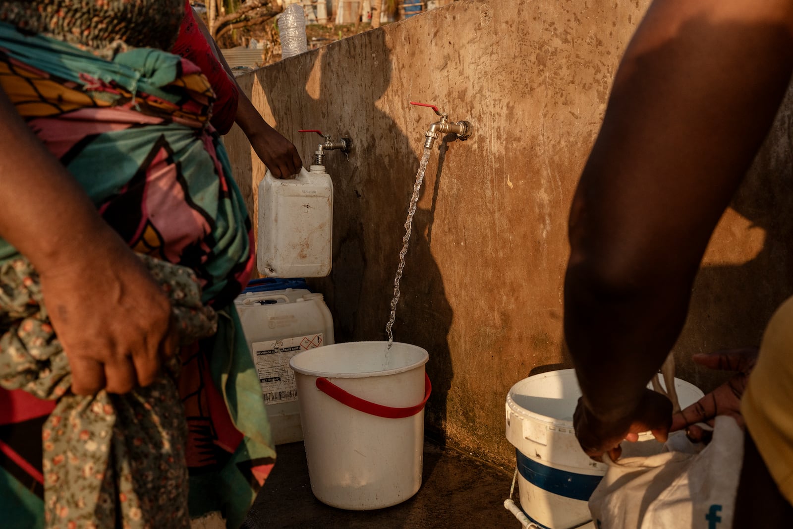 People line up to collect water in Barakani, Mayotte, home Saturday, Dec. 21, 2024. (AP Photo/Adrienne Surprenant)