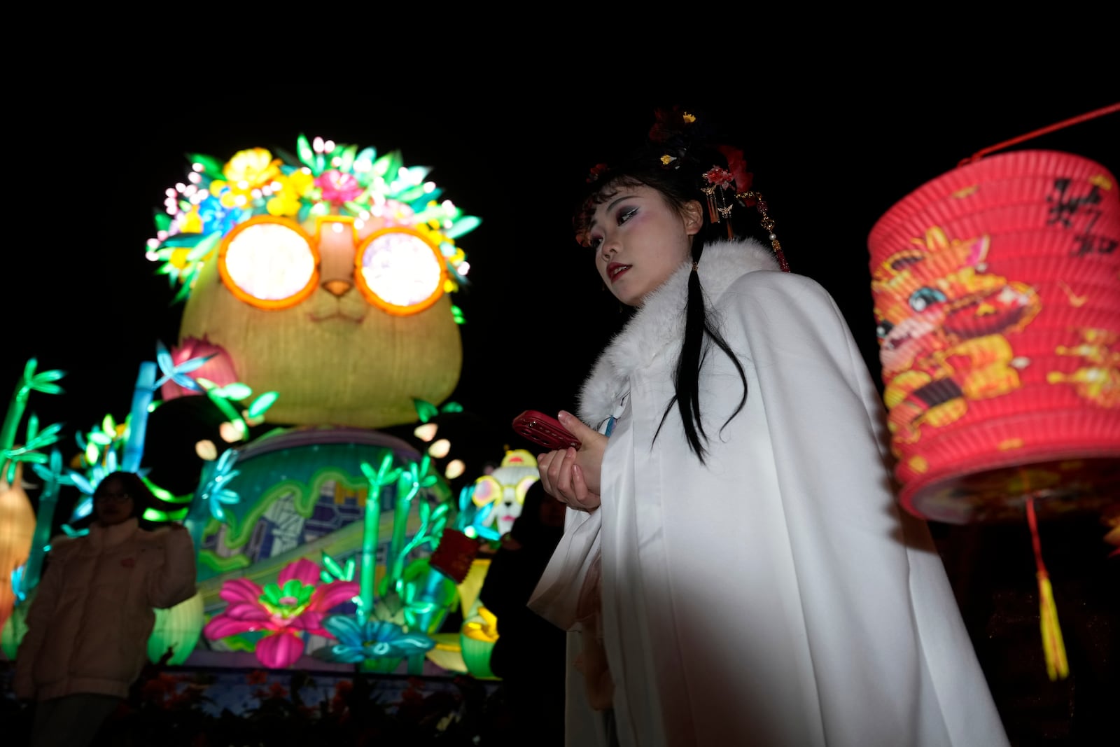 A woman in traditional costume walks past a panda decoration at the Lantern Festival during Yuanxiao, the fifteen day of the Lunar New Year in Beijing, Wednesday, Feb. 12, 2025. (AP Photo/Ng Han Guan)