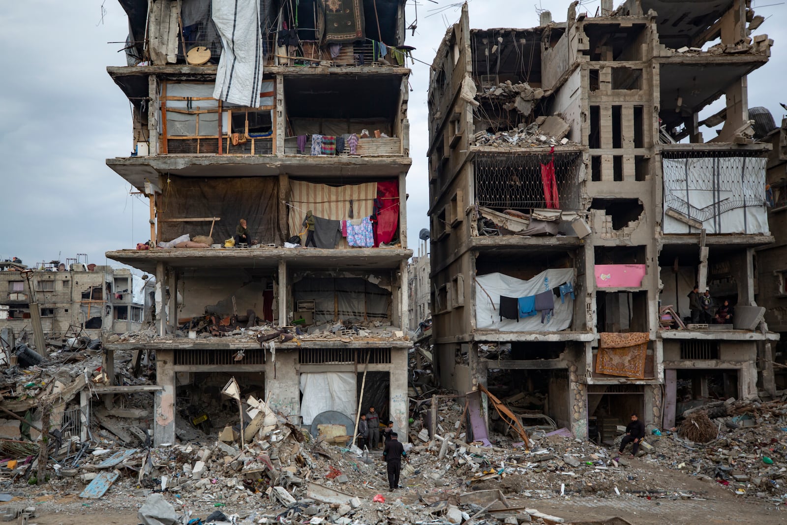 Palestinians sit in their partially standing homes, covered with sheets as makeshift walls, in an area largely destroyed by the Israeli army's air and ground offensive in Jabaliya, Gaza Strip, Tuesday, Feb. 11, 2025. (AP Photo/Jehad Alshrafi)