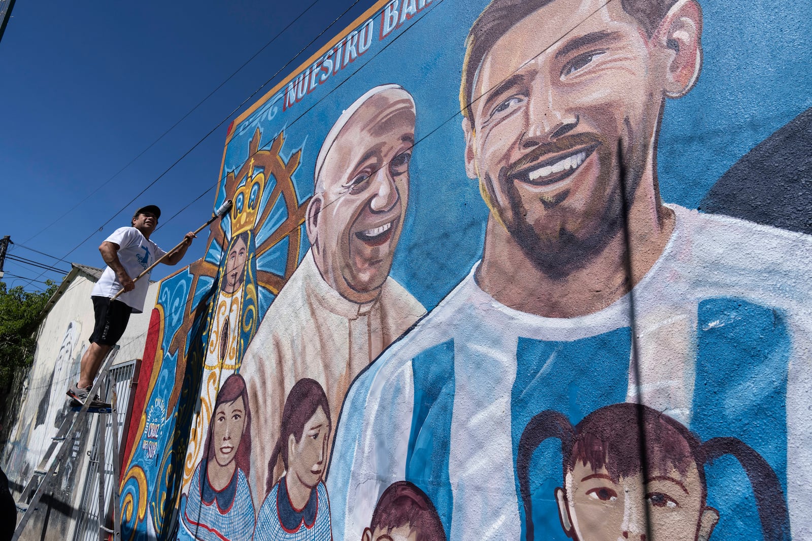 Roberto Coria preserves a mural depicting Pope Francis and soccer star Lionel Messi in Buenos Aires, Argentina, Wednesday, Feb. 19, 2025. (AP Photo/Rodrigo Abd)