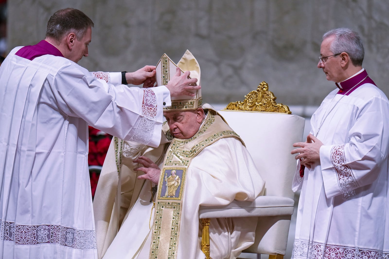 Pope Francis is helped by masters of ceremonies Massimiliano Matteo Boiardi, left, and Diego Giovanni Ravelli, right, as he presides over the Christmas Eve Mass in St. Peter's Basilica at The Vatican, Tuesday, Dec. 24, 2024, after opening the basilica's holy door marking the start of the Catholic jubilar year 2025. (AP Photo/Andrew Medichini)