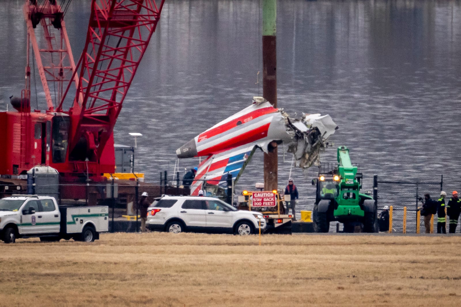 A crane offloads a piece of wreckage from a salvage vessel onto a flatbed truck, near the wreckage site in the Potomac River of a mid-air collision between an American Airlines jet and a Black Hawk helicopter, at Ronald Reagan Washington National Airport, Wednesday, Feb. 5, 2025, in Arlington, Va. (AP Photo/Ben Curtis)