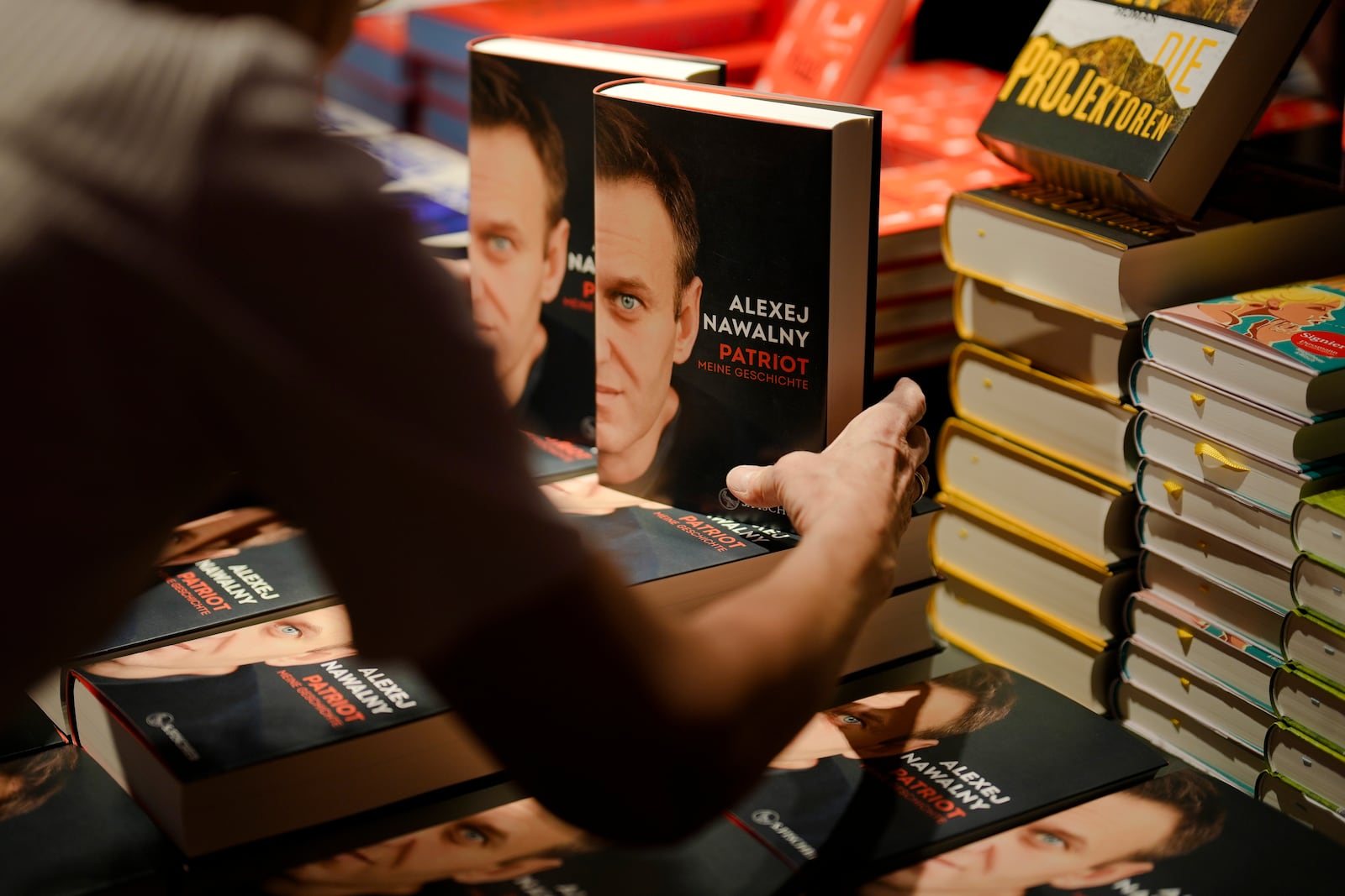 A woman arranges copies of the late Russian opposition leader Alexei Navalny's memoir entitled 'Patriot' are put display on the first day of sale in a bookshop in Berlin, Germany, Tuesday, Oct. 22, 2024. (AP Photo/Markus Schreiber)