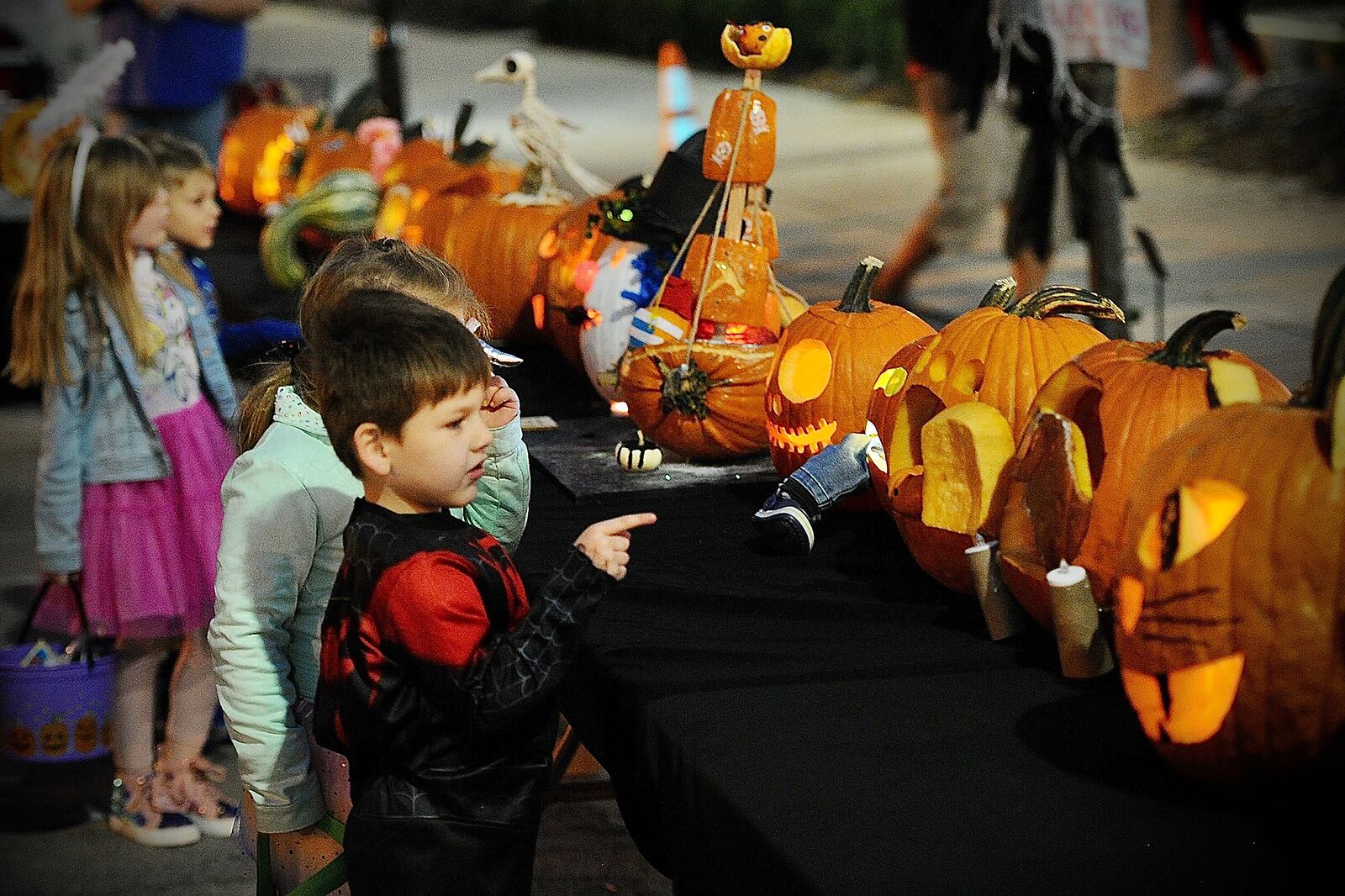 Children look over the pumpkins in the pumpkin carving contest Saturday during the New Carlisle Halloween Night Market. Marshall Gorby/Staff