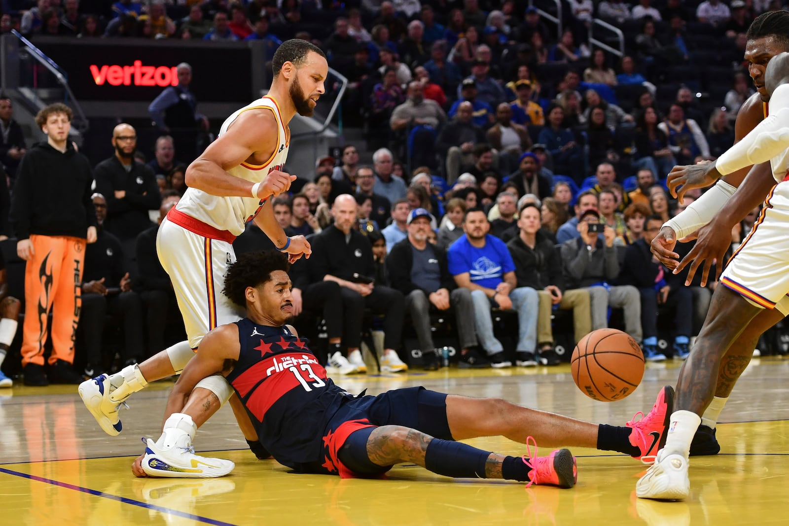 Washington Wizards' Jordan Poole (13) falls backward onto the right knee of Golden State Warriors' Stephen Curry, top left, in the fourth quarter of an NBA basketball game in San Francisco, Saturday, Jan. 18, 2025. (Jose Carlos Fajardo/Bay Area News Group via AP)