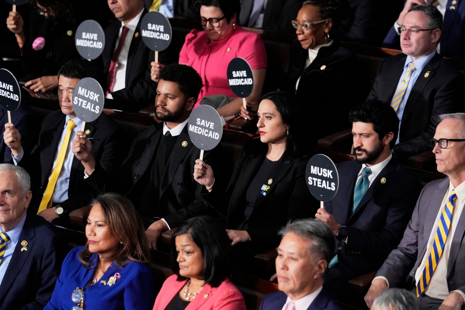 Members of Congress hold up signs as President Donald Trump addresses a joint session of Congress at the Capitol in Washington, Tuesday, March 4, 2025. (AP Photo/J. Scott Applewhite)