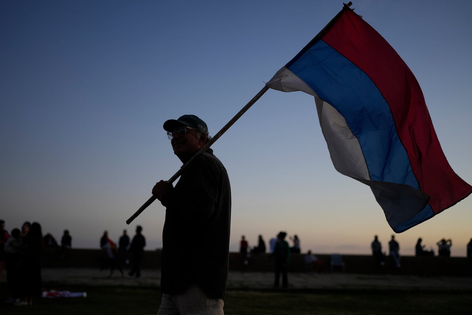 A man holds a Frente Amplio party flag during general elections in Montevideo, Uruguay, Sunday, Oct. 27, 2024. (AP Photo/Natacha Pisarenko)