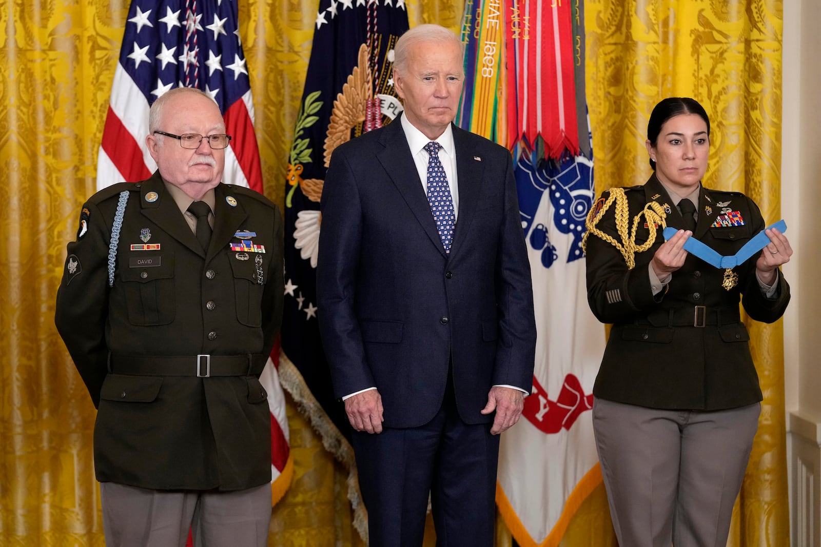 President Joe Biden, center, listens to the citation before presenting the Medal of Honor, the nation's highest military decoration, to then-Private First Class Kenneth J. David, left, during a ceremony in the East Room of the White House in Washington, Friday, Jan. 3, 2025. (AP Photo/Susan Walsh)