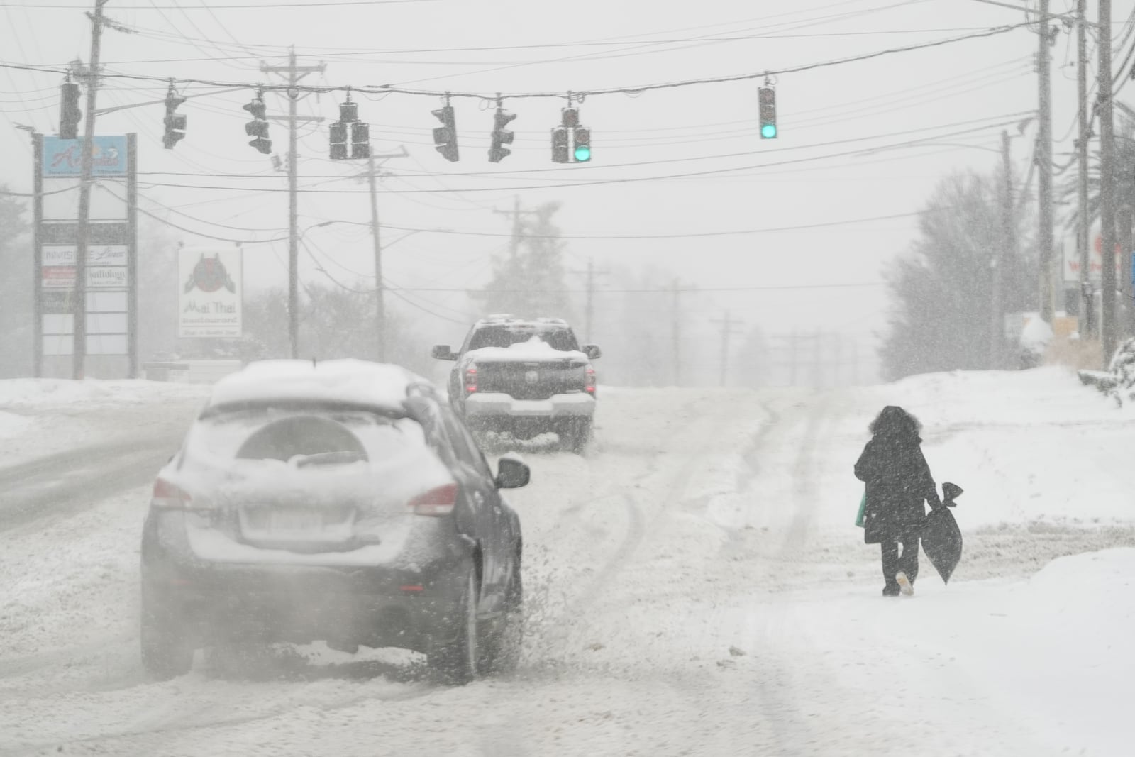 Heavy snow falls as a person walks along U.S. Route 42 in Florence, Ky., Monday, Jan. 6, 2025. (AP Photo/Carolyn Kaster)