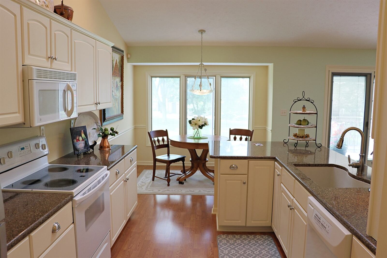 The breakfast room is an extension of the kitchen, which has white cabinetry and dark quartz counters.