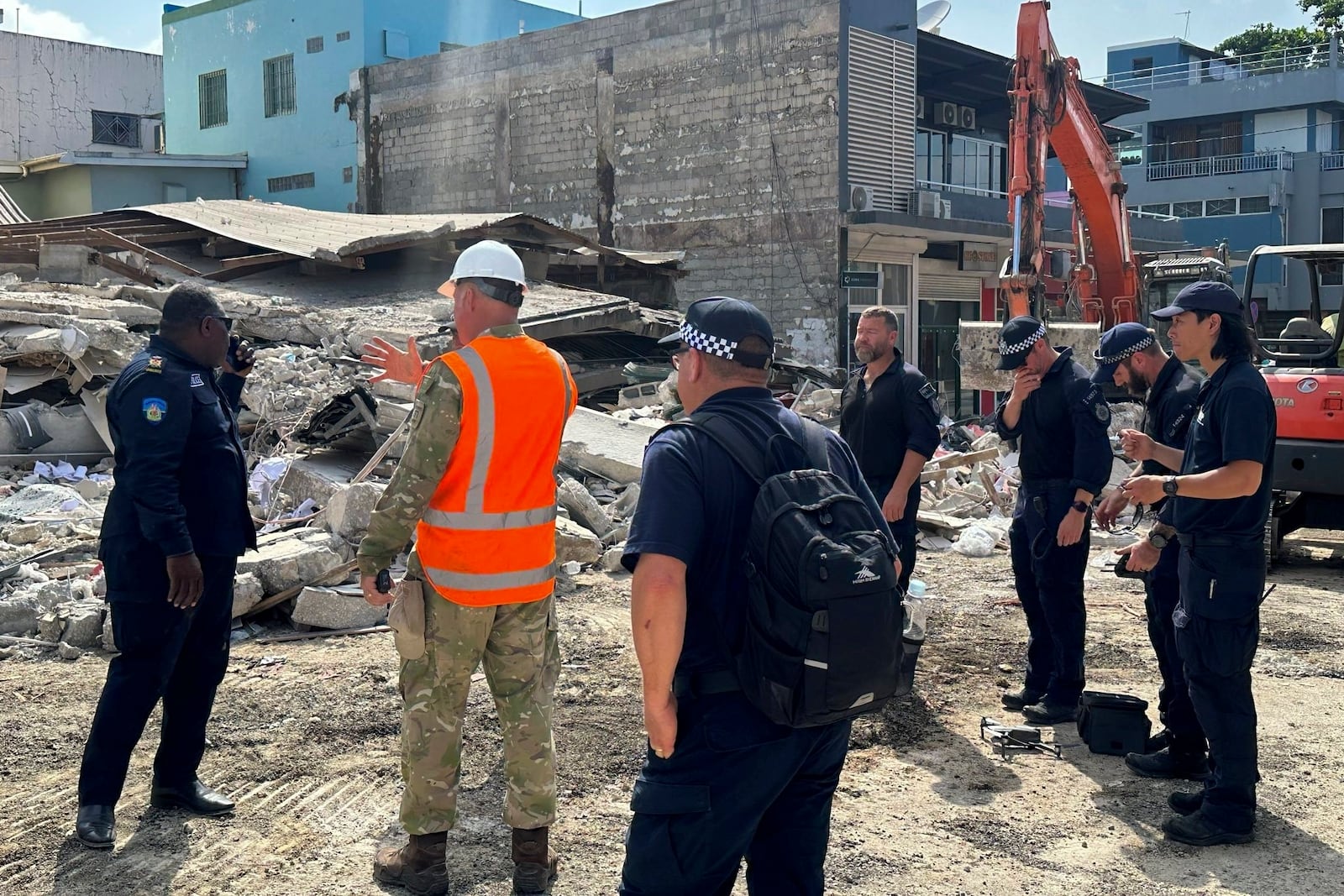 Members of Australia's Federal Police and other rescue workers stand by a collapsed building in Port Vila, Vanuatu, Thursday, Dec. 19, 2024, following a magnitude 7.3 earthquake that struck just off the coast of Vanuatu in the South Pacific Ocean, Tuesday, Dec. 17. (Australian Federal Police via AP)