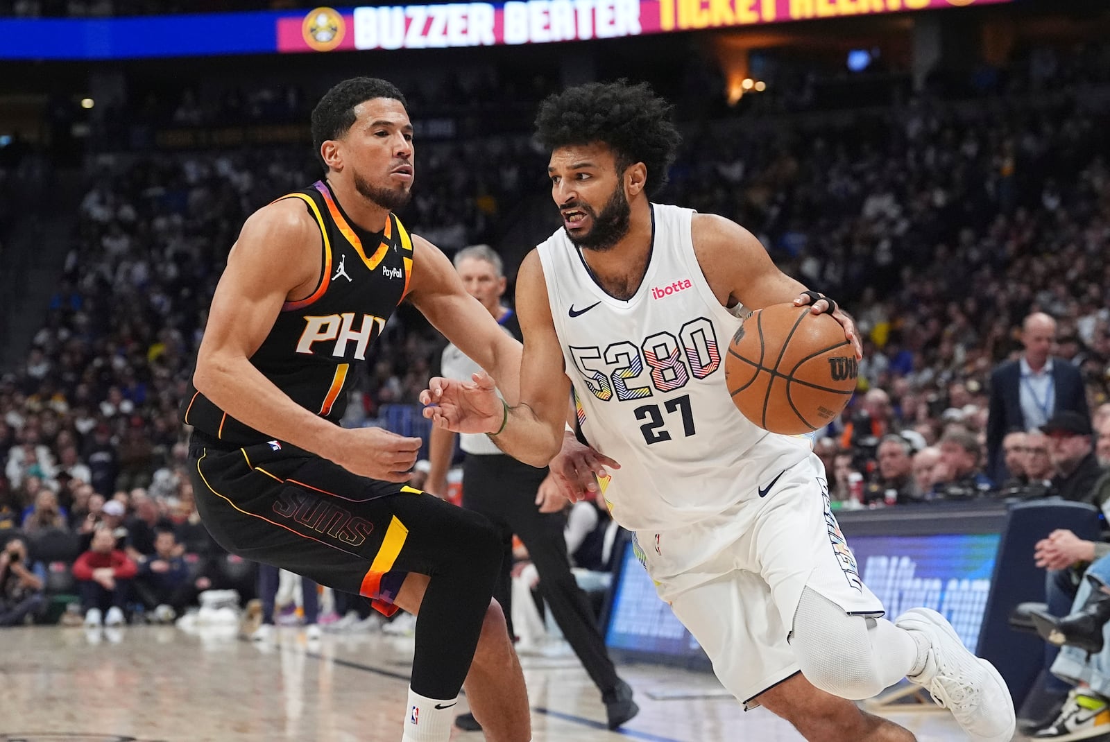 Denver Nuggets guard Jamal Murray, right, drives to the basket past Phoenix Suns guard Devin Booker in the first half of an NBA basketball game Friday, March 7, 2025, in Denver. (AP Photo/David Zalubowski)