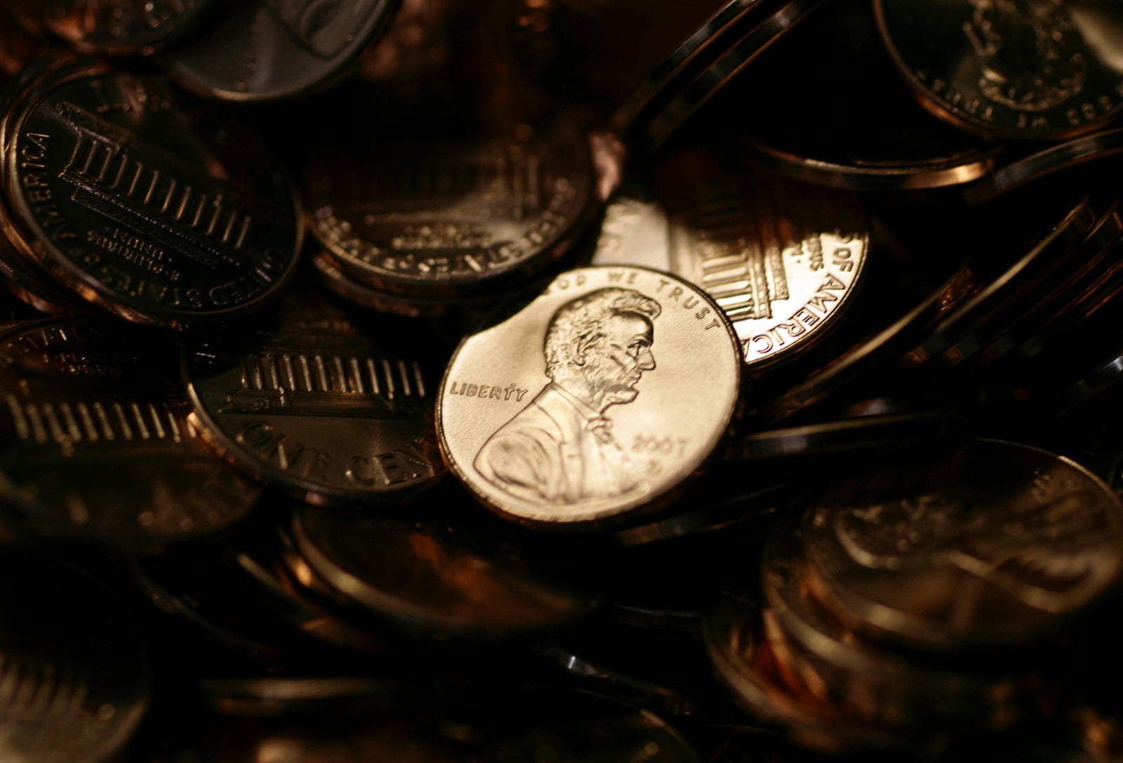 FILE - A lone penny is illuminated in a bin of completed pennies at the U.S. Mint in Denver, Aug. 15, 2007. (AP Photo/David Zalubowski)