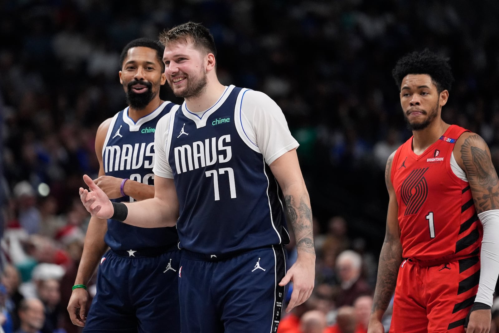 Dallas Mavericks guard Luka Doncic (77) shares a laugh with guard Spencer Dinwiddie (26) as Portland Trail Blazers guard Anfernee Simons (1) looks on during the second half of an NBA basketball game Monday, Dec. 23, 2024, in Dallas. (AP Photo/LM Otero)