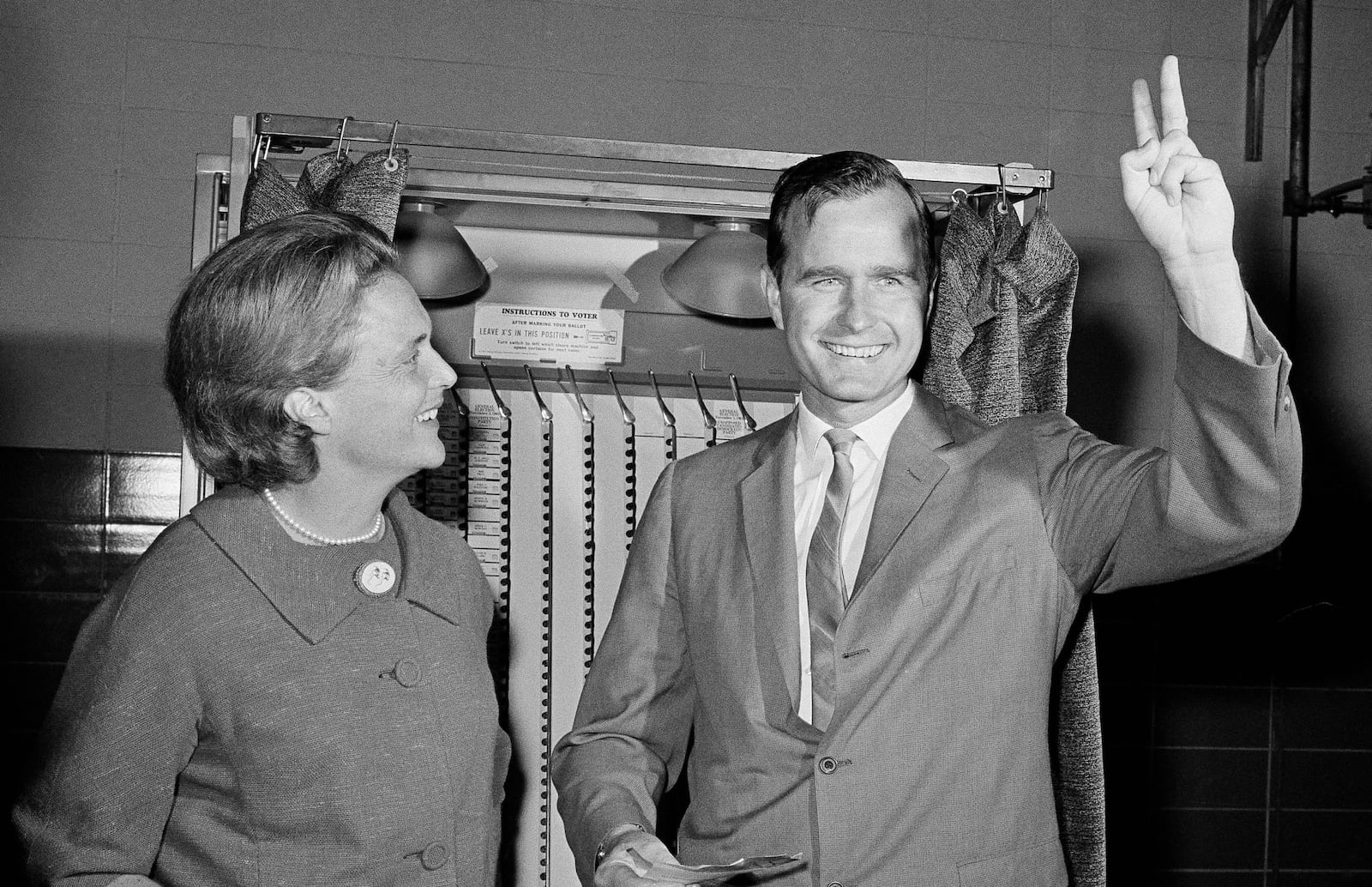 Republican Senatorial candidate George Bush shows a victory sign as he and his wife Barbara stand in front of a vote machine November 3, 1964 in Houston.