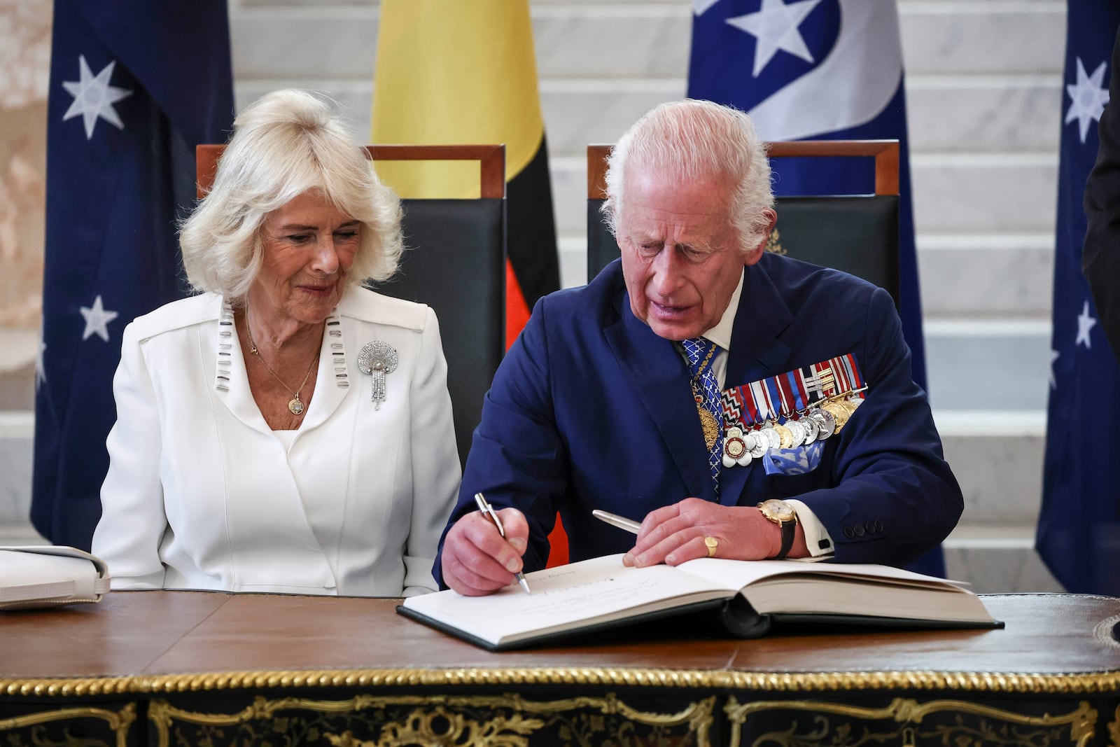 Britain's King Charles III and Queen Camilla sign a visitors' book in the Marble Foyer of Parliament House in Canberra, Australia, Monday, Oct. 21, 2024. (David Gray/Pool Photo via AP)