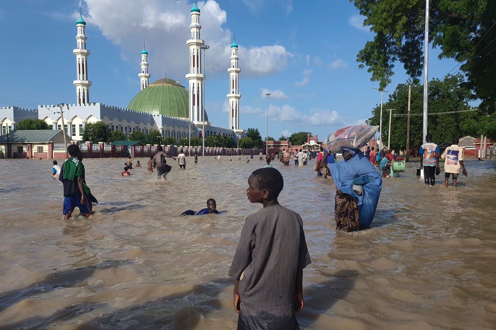 FILE - People walk through floodwaters following a dam collapse in Maiduguri, Nigeria, Sept 10, 2024. (AP Photos/ Joshua Olatunji, File)