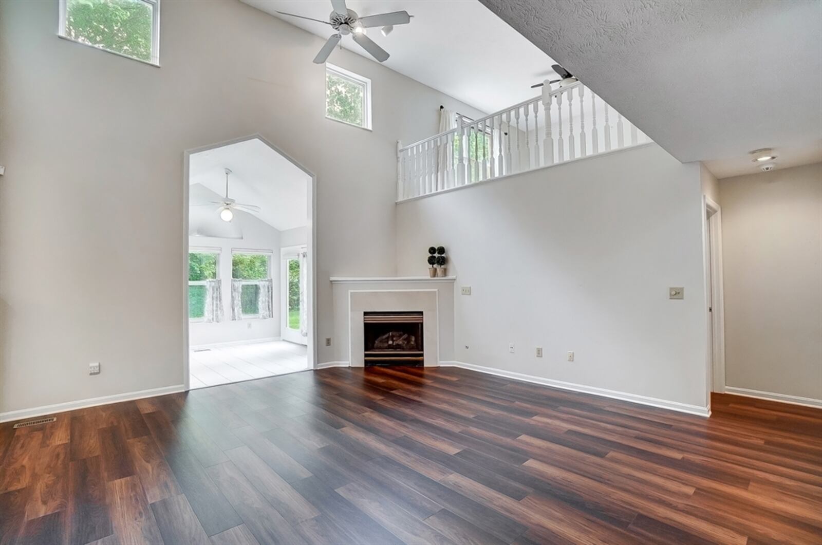 The two-story great room features a corner gas fireplace with wood-capped mantel and ceramic-tile surround. 