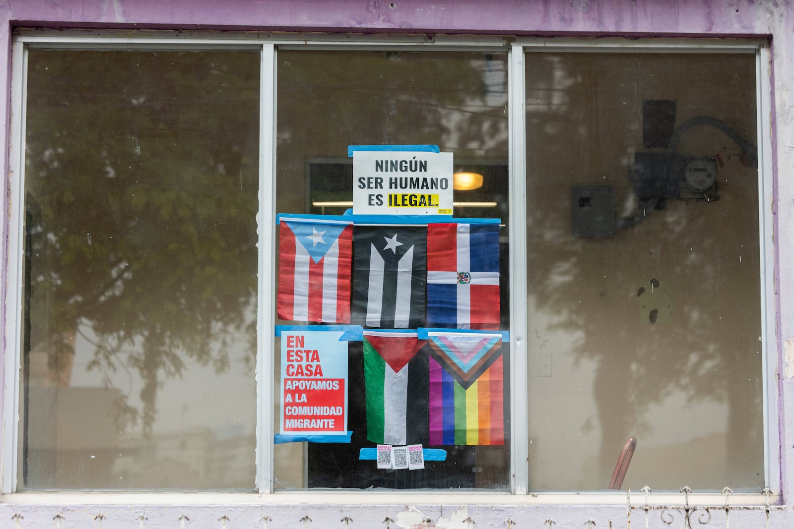 A sign in Spanish that reads, "No human being is illegal," adorns a window in Barrio Obrero, San Juan, Puerto Rico, Friday, March 14, 2025. (AP Photo/Alejandro Granadillo)