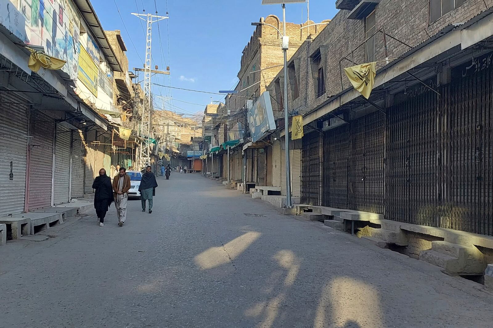 Local residents walk in a market, which closed due to strike called by traders as a protest against a gunmen firing incident, in Parachinar, main town of Kurram district of Pakistan's northwestern Khyber Pakhtunkhwa province, Friday, Nov. 22, 2024. (AP Photo/Hussain Ali)