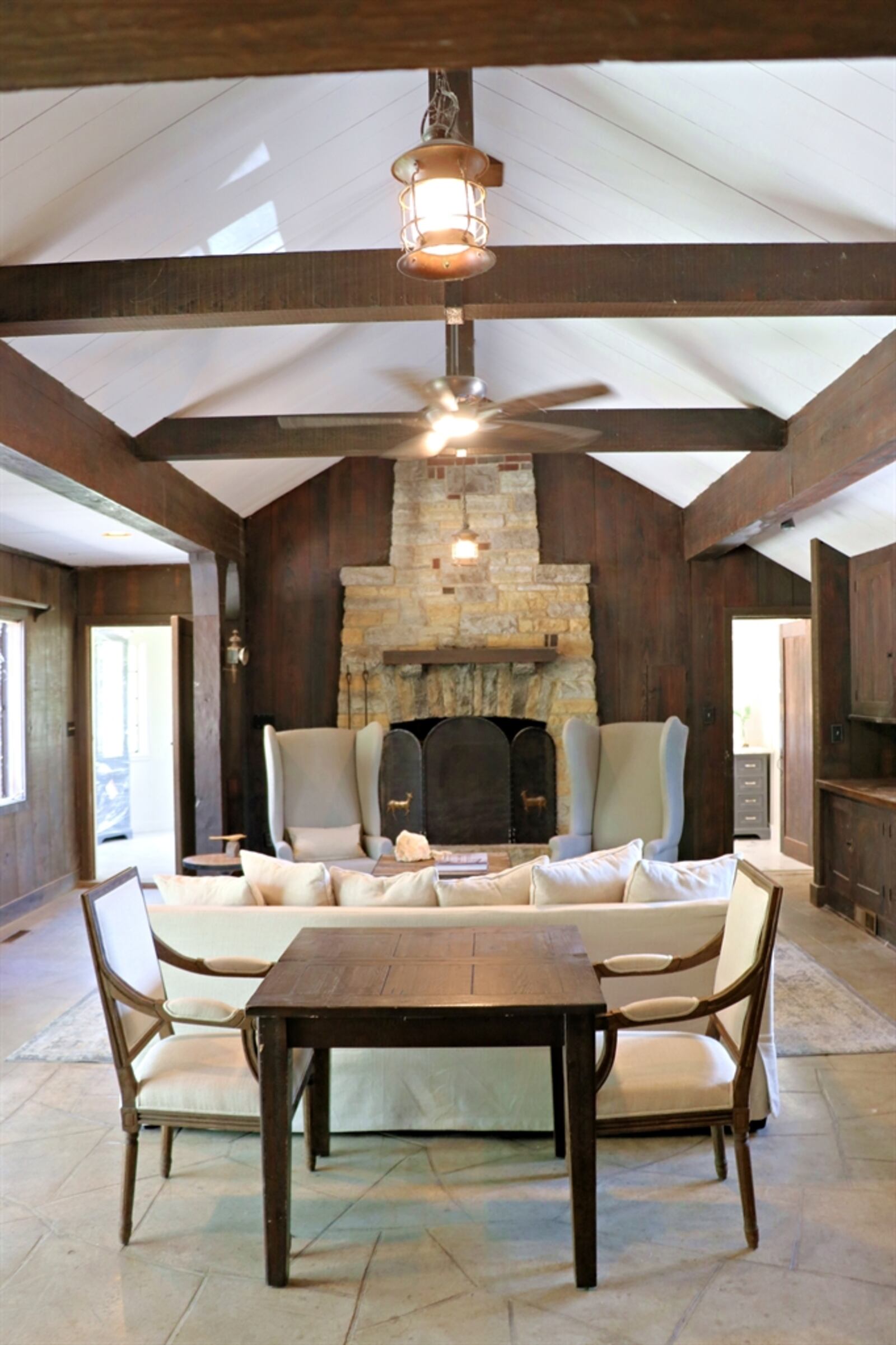 The great room is on the upper level and features vaulted ceilings, original wood beams and a large stone fireplace. 