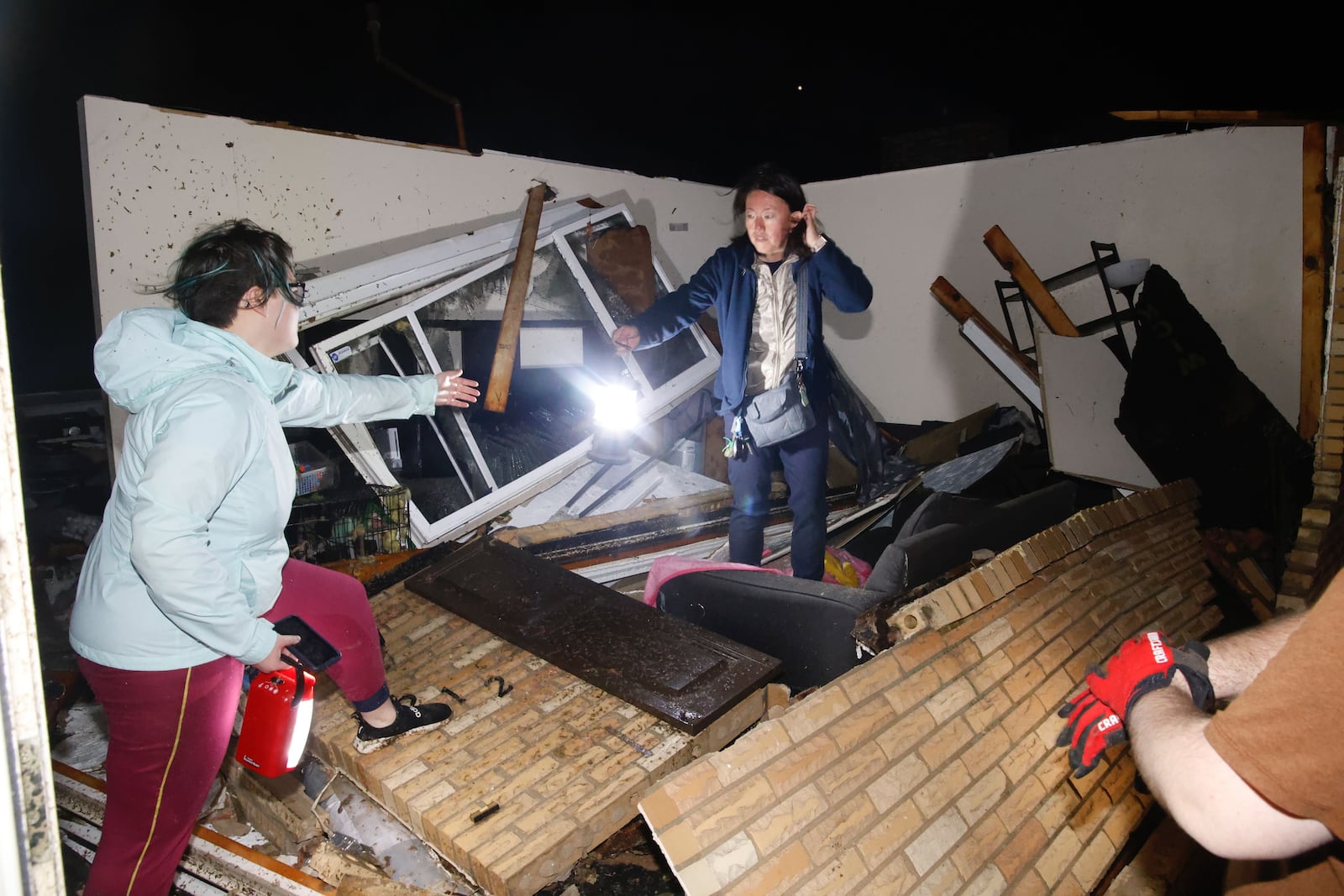 Emi Campbell and her daughter Emma search their Ridge Road house early Wednesday morning, Feb. 28, 2024, after it sustained extensive damage from a possible tornado. BILL LACKEY/STAFF