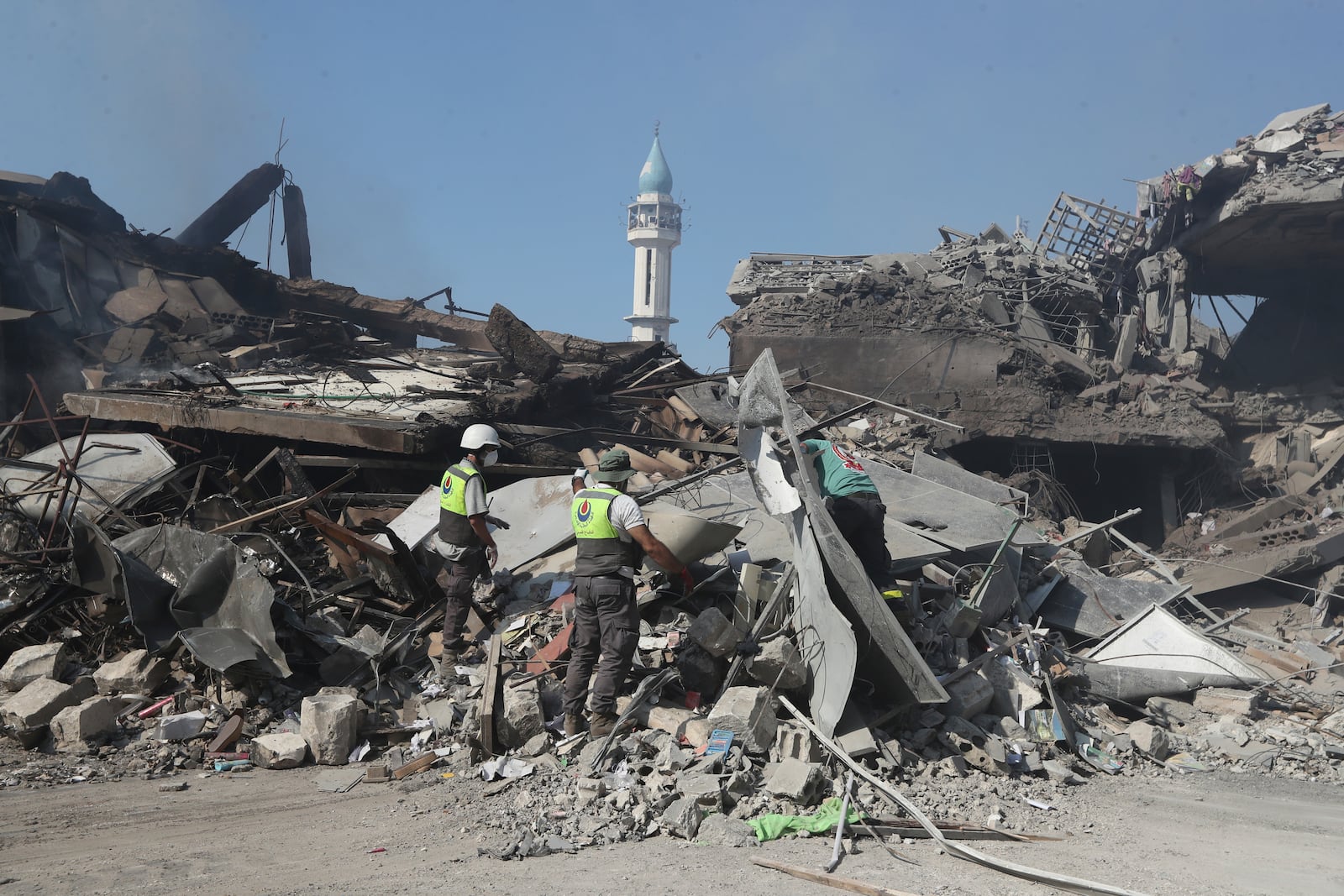 Hezbollah rescue workers search for victims on the rubble of destroyed buildings at commercial street that was hit Saturday night by Israeli airstrikes, in NAbatiyeh town, south Lebanon, Sunday, Oct. 13, 2024. (AP Photo/Mohammed Zaatari)