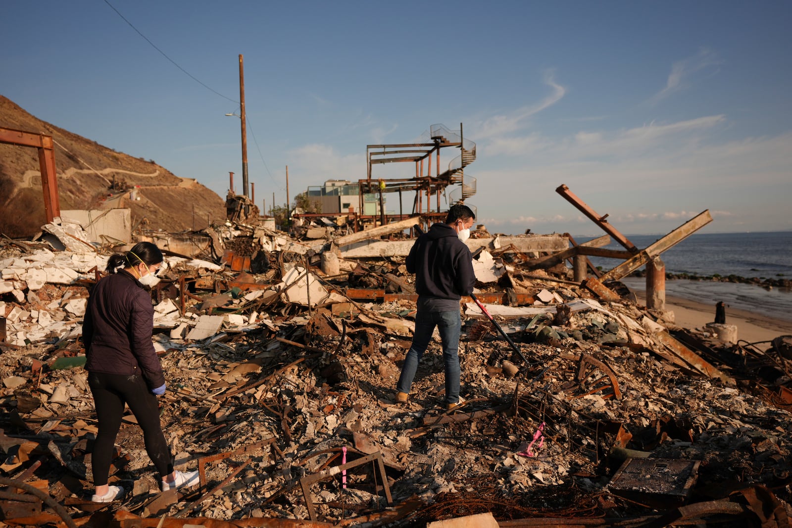 FILE - Tony Lai, center, rakes through the remains of his fire-ravaged beachfront property with his wife Everlyn in the aftermath of the Palisades Fire Tuesday, Jan. 28, 2025 in Malibu, Calif. (AP Photo/Jae C. Hong, File)