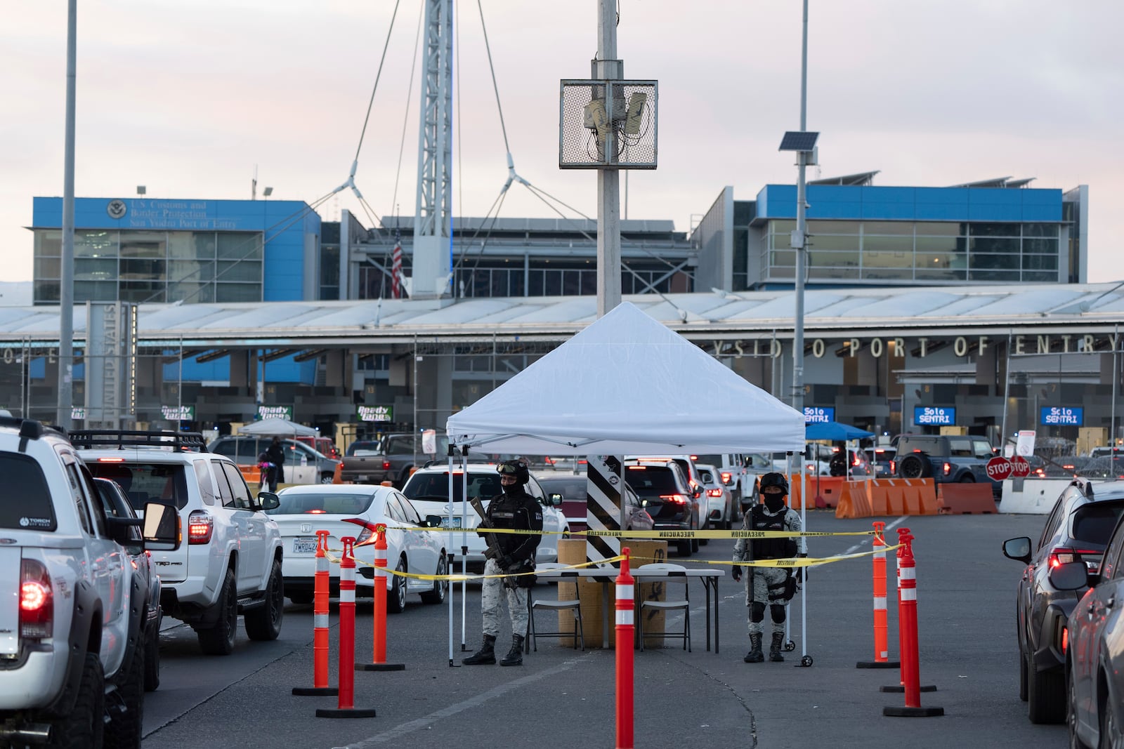 FILE - Members of the Mexican National Guard review cars as they line up to cross the border into the United States at the San Ysidro Port of Entry, Dec. 3, 2024, in Tijuana, Mexico. (AP Photo/Gregory Bull, File)