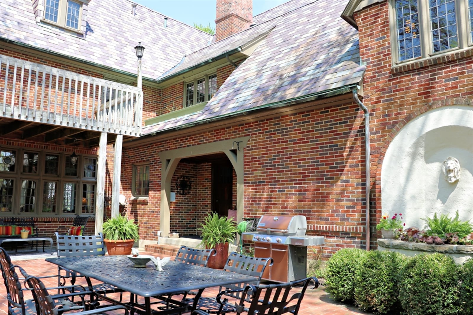 Patio doors open off the enclosed porch out to a large paver-brick terrace surrounded by a curved pergola with bench seating.